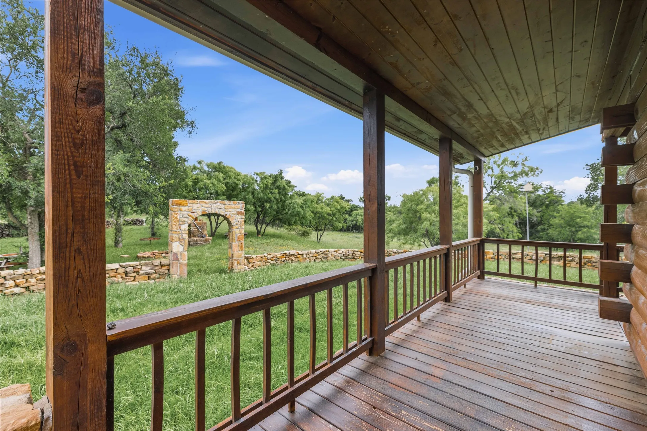Spacious wood-decked porch with a natural wood-plank ceiling, wooden railings, and substantial support posts