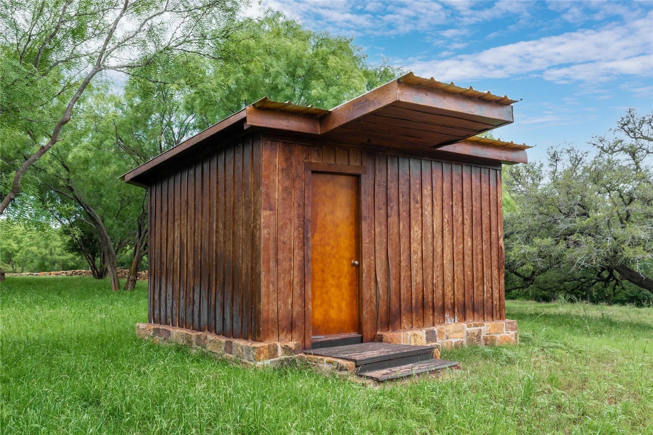 Wood-paneled exterior structure featuring a metal roof and a stone foundation