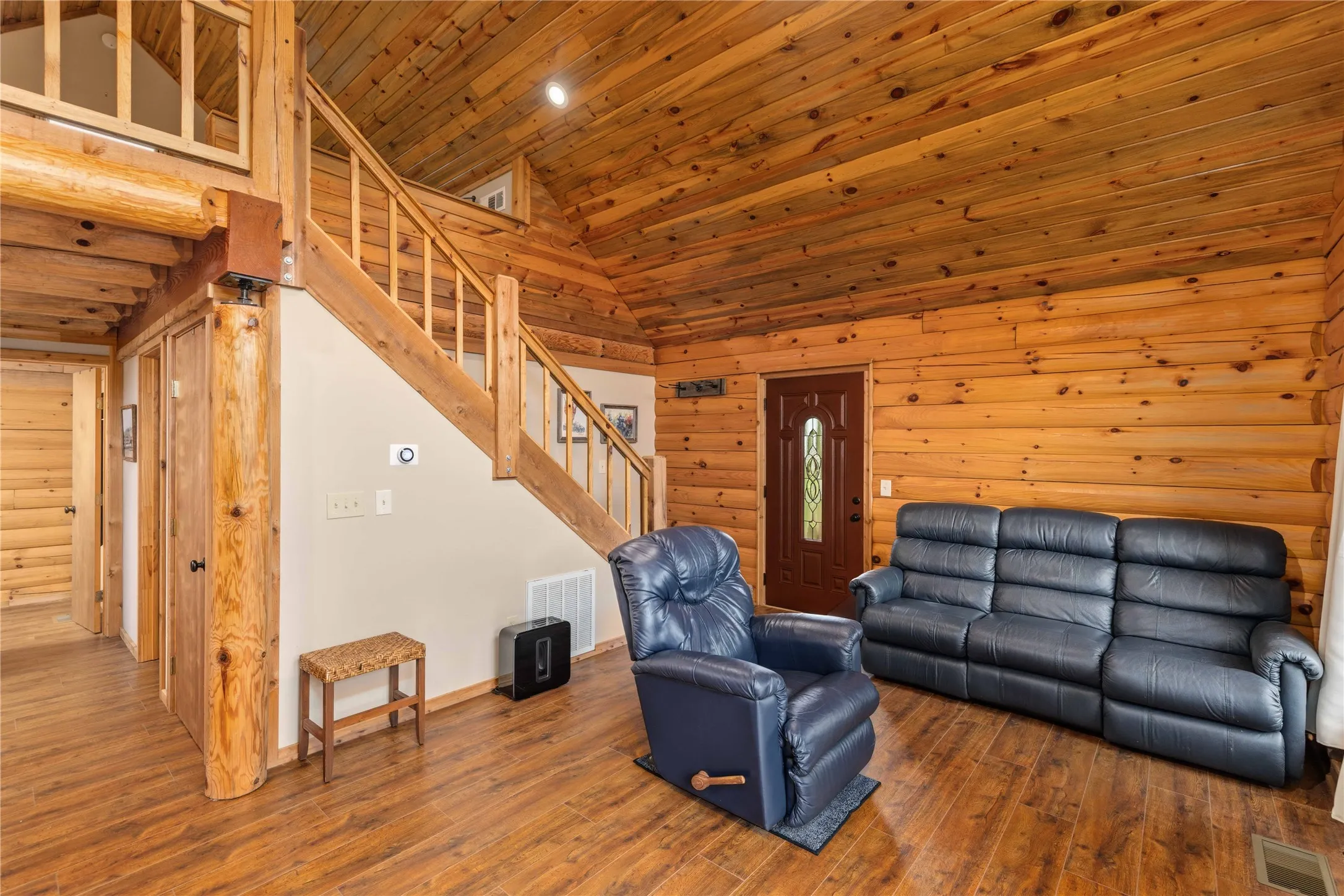 Interior featuring extensive log wall construction, wood-finish flooring, a wood staircase, and a wood plank ceiling