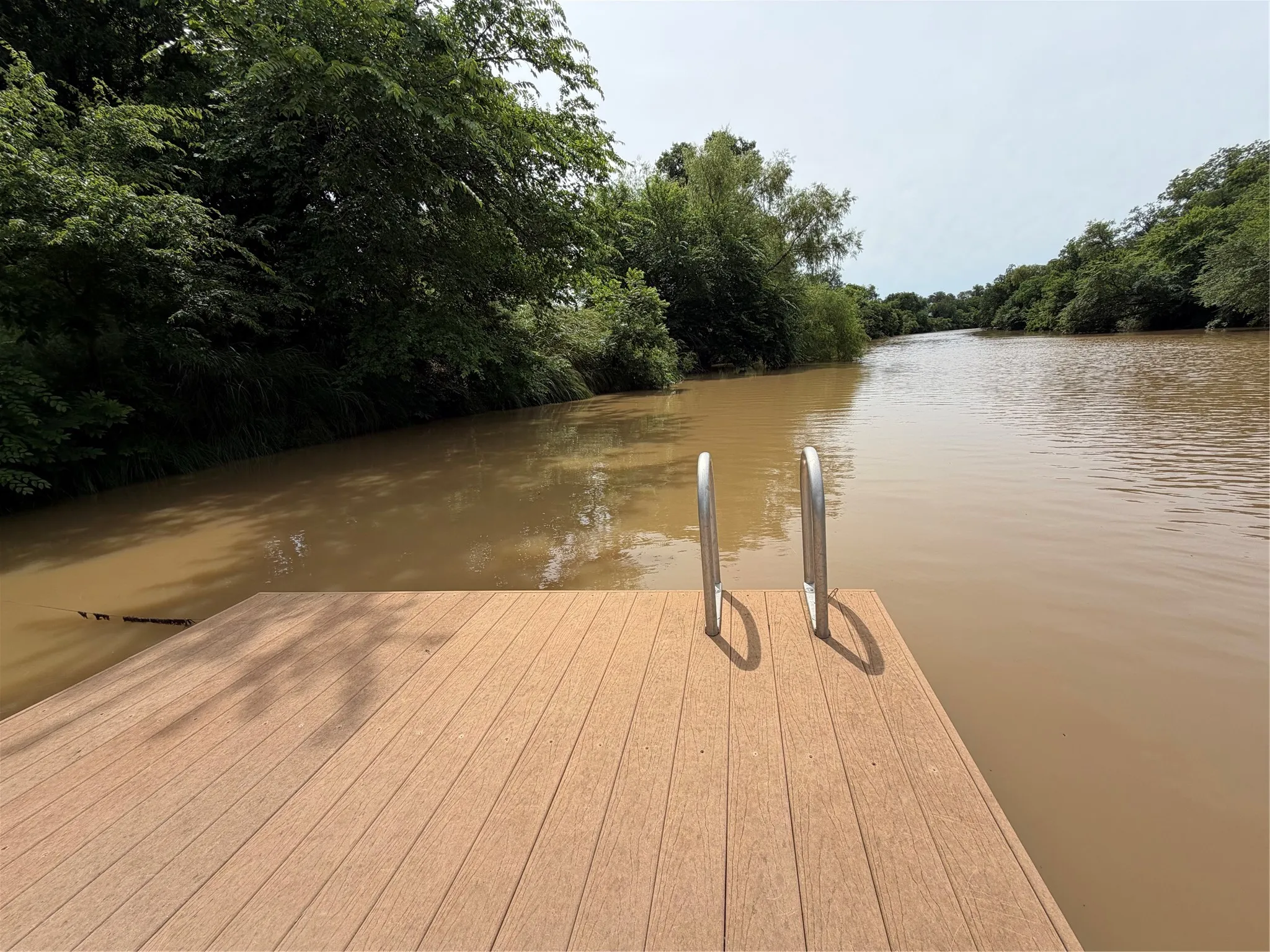 Waterfront dock featuring wood-finish decking and stainless steel ladder