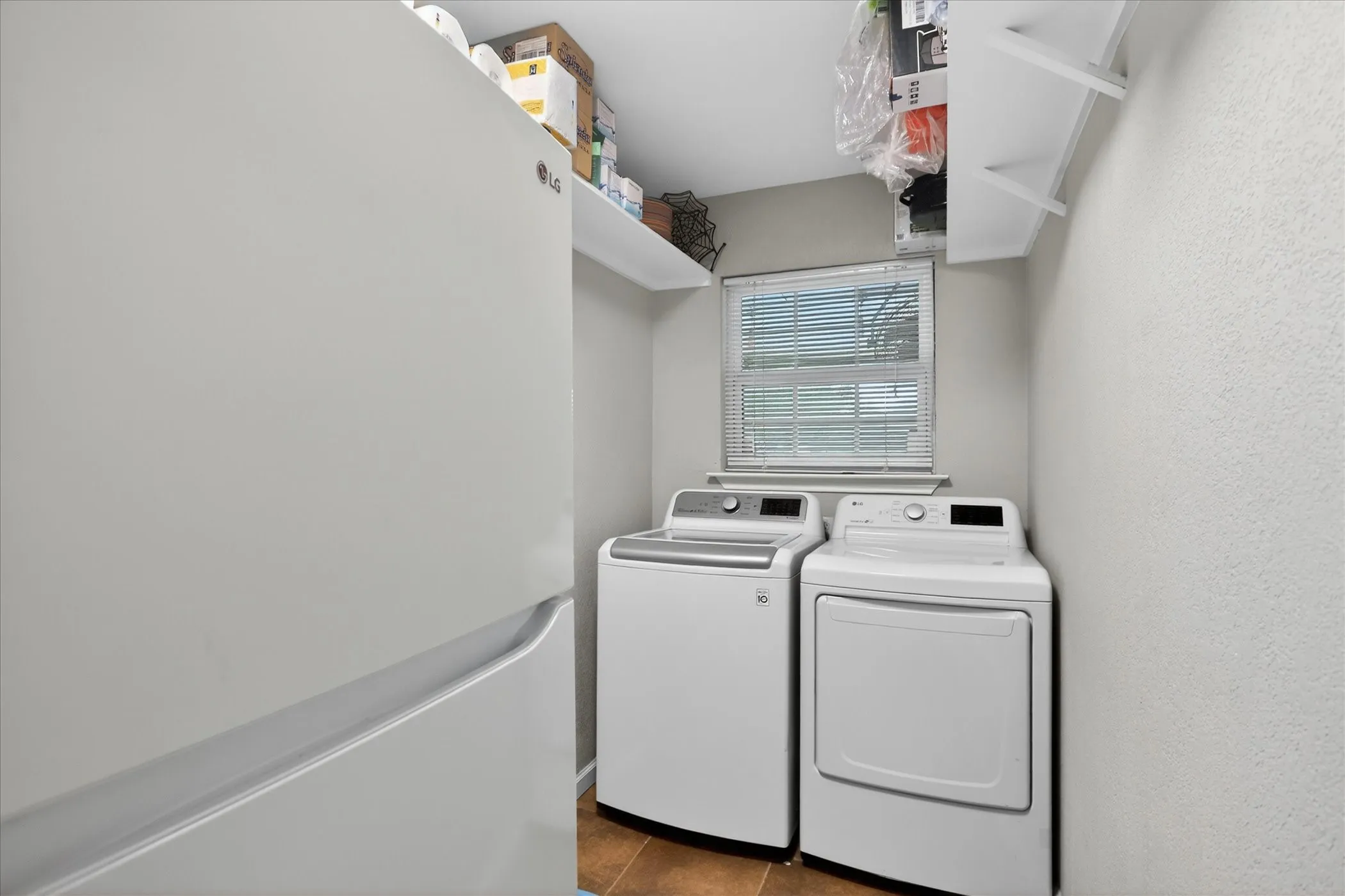 Utility room has space for 2nd refrigerator. Shelves along the walls for storage.