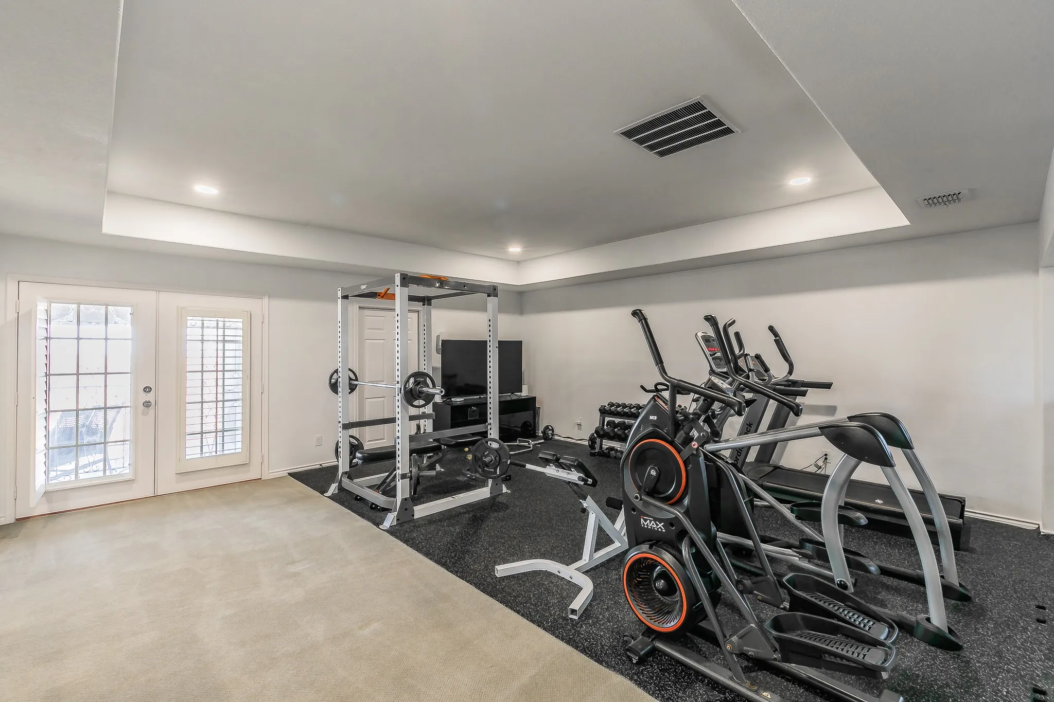 Exercise room featuring visible vents, baseboards, recessed lighting, french doors, and a raised ceiling