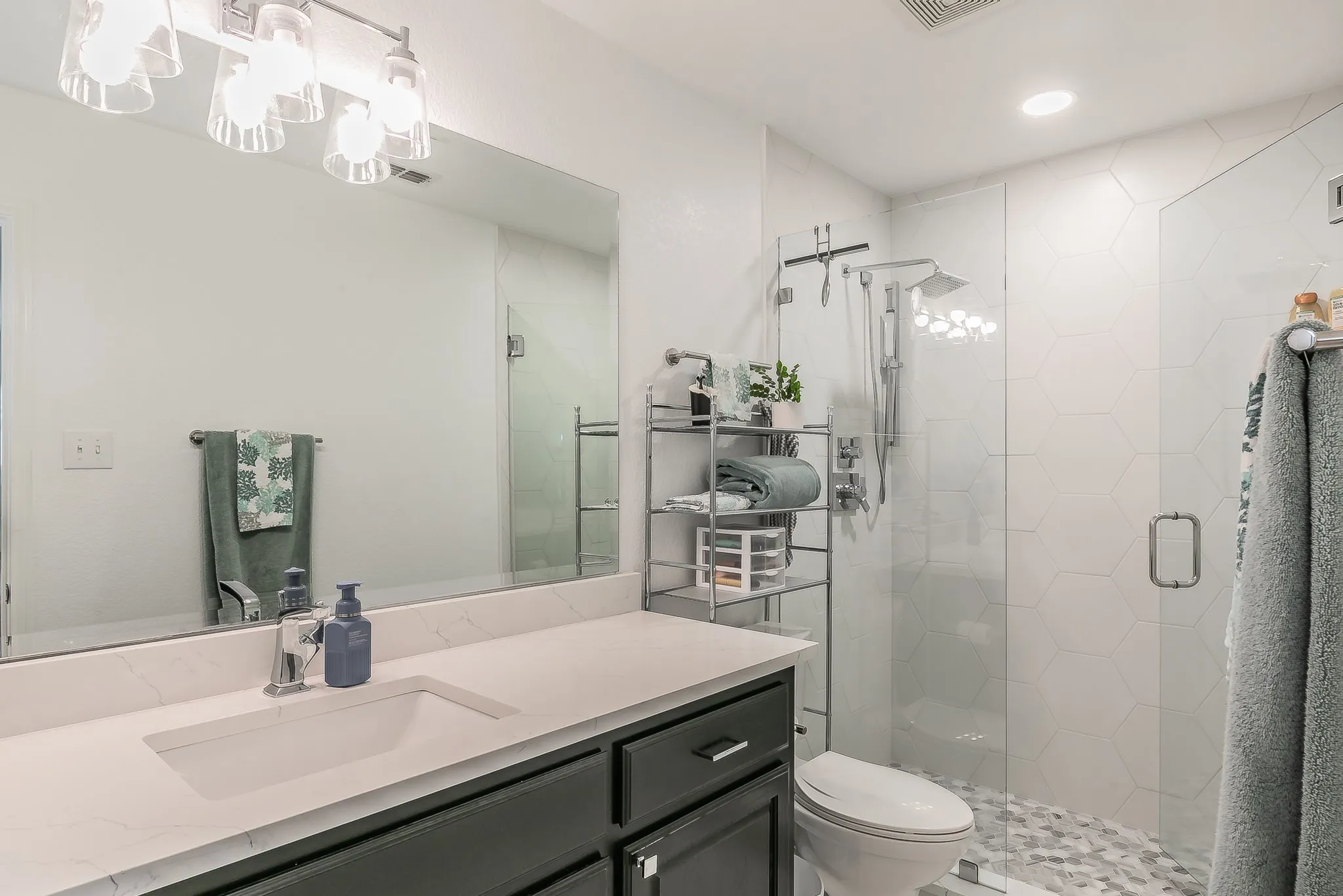 Bathroom featuring vanity, a shower stall, toilet, and visible vents
