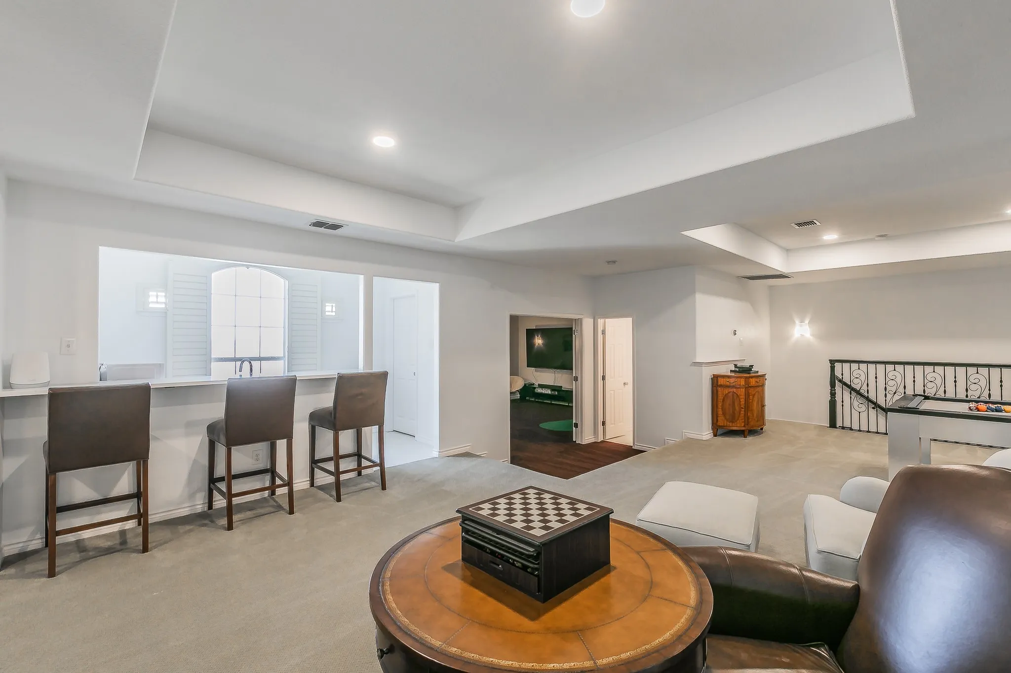 Living area with a raised ceiling, recessed lighting, visible vents, and light carpet