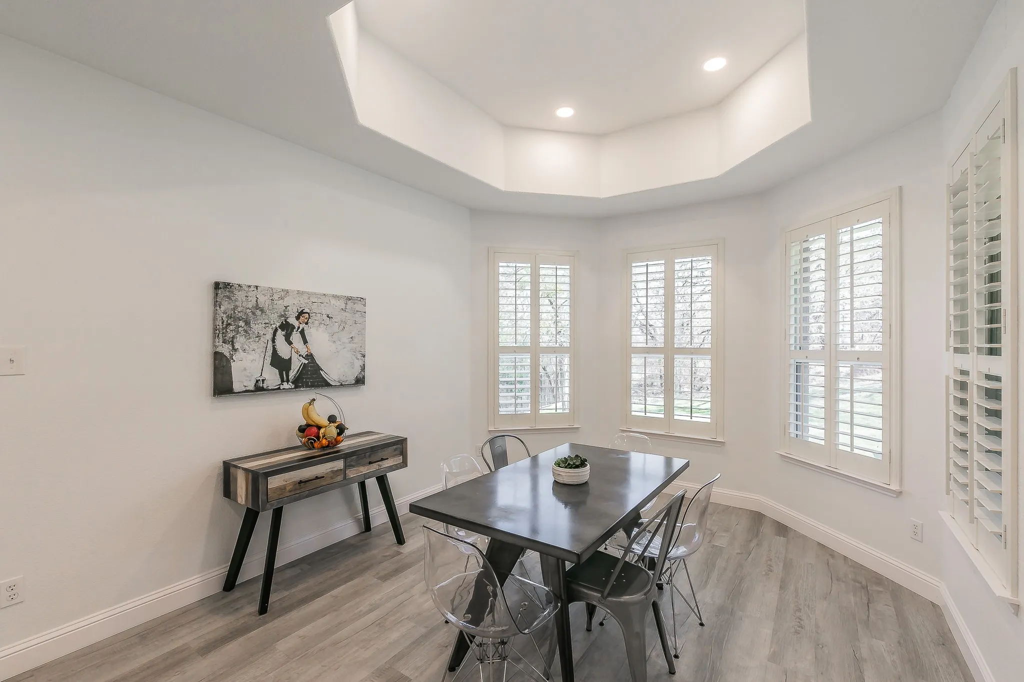 Dining space with a tray ceiling, light wood finished floors, baseboards, and a wealth of natural light