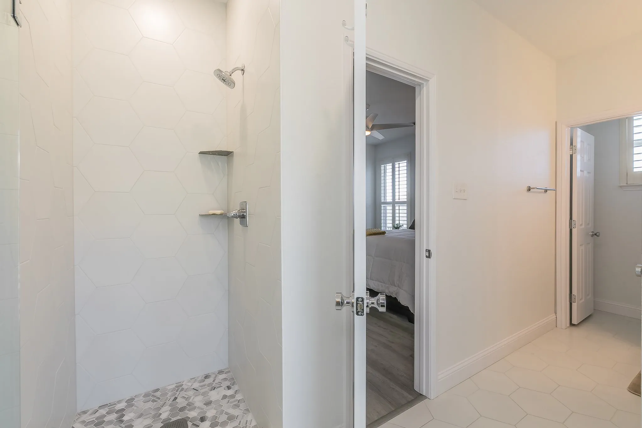 Ensuite bathroom to first floor bedroom featuring a ceiling fan, baseboards, a tile shower, and connected bathroom