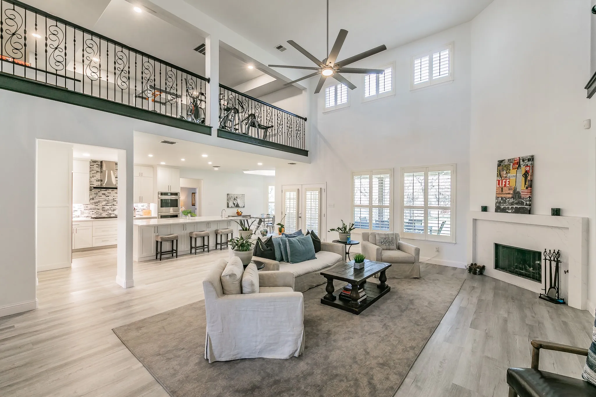 Living area featuring a fireplace, baseboards, light wood-type flooring, and ceiling fan