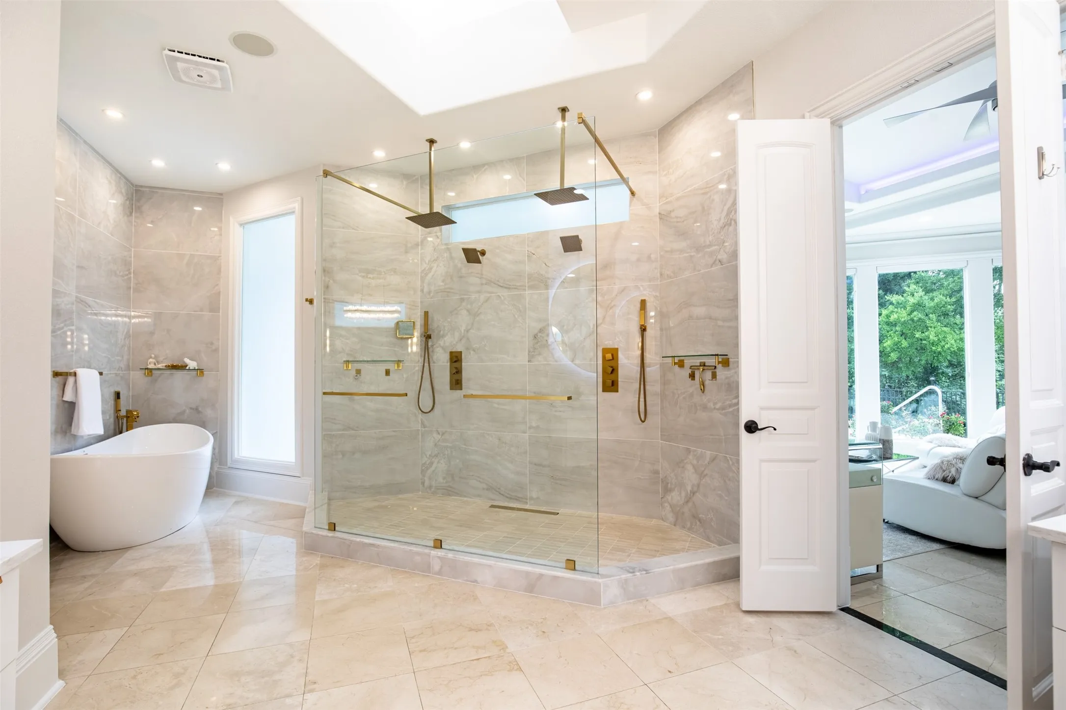 Spacious bathroom featuring a frameless glass shower enclosure with dual rainfall showerheads and gold-finish fixtures