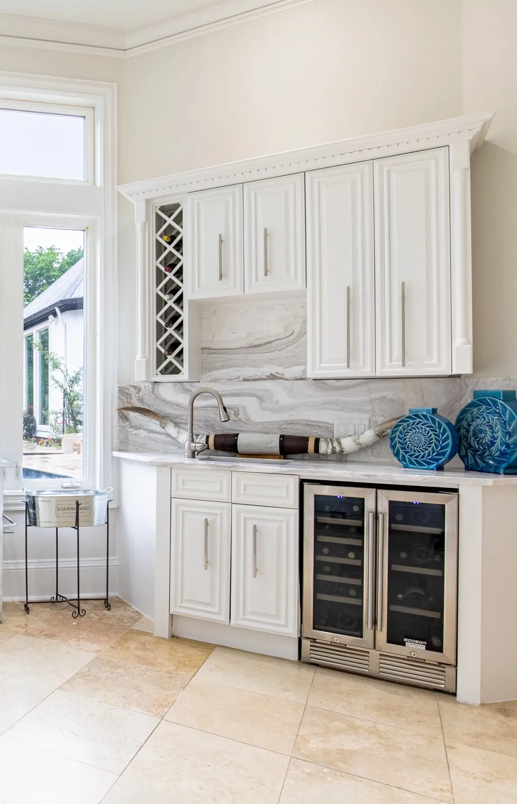 Built-in wet bar featuring white cabinetry with brushed nickel hardware, a stone countertop, and a matching stone backsplash