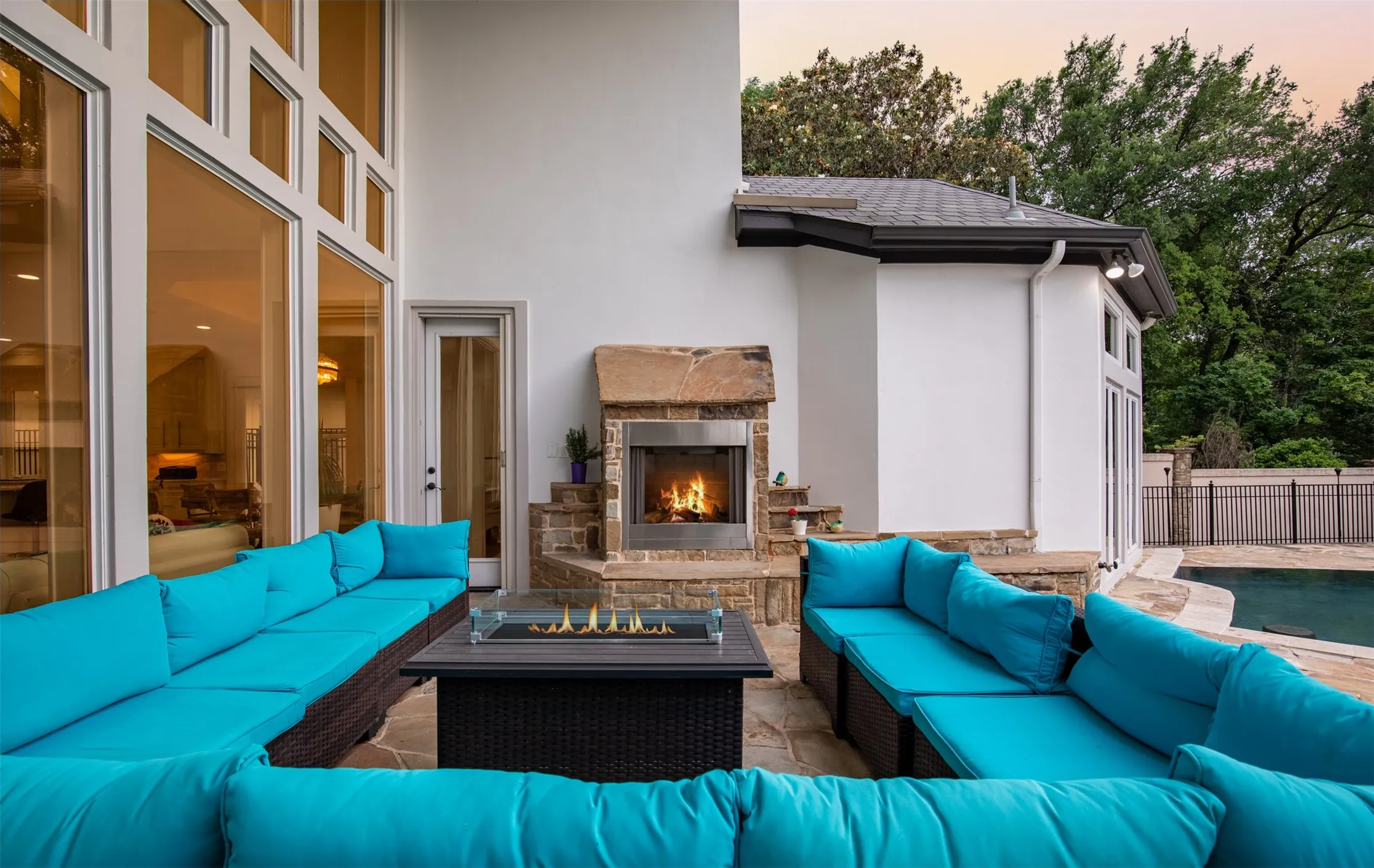 Outdoor entertaining area featuring a stone fireplace, expansive glass doors, and flagstone patio