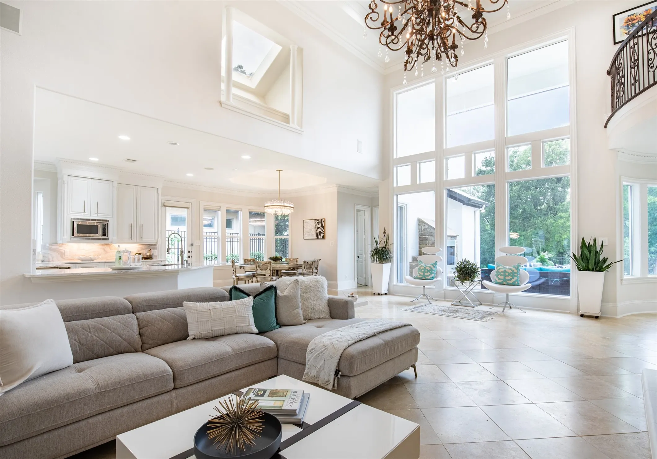 Two-story living area with expansive window wall, ornate chandelier, and tiled flooring