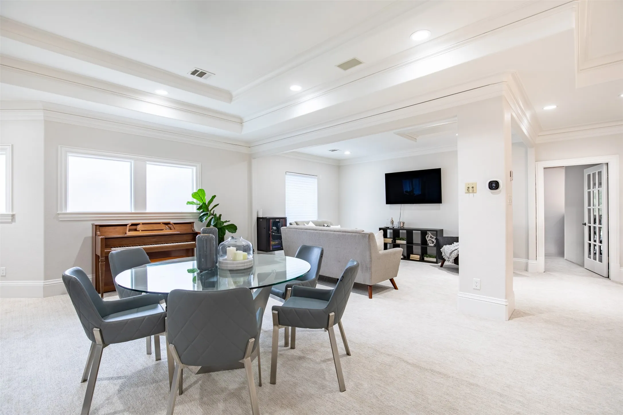 Spacious open-concept room featuring light-toned carpet flooring, recessed lighting, and multiple windows