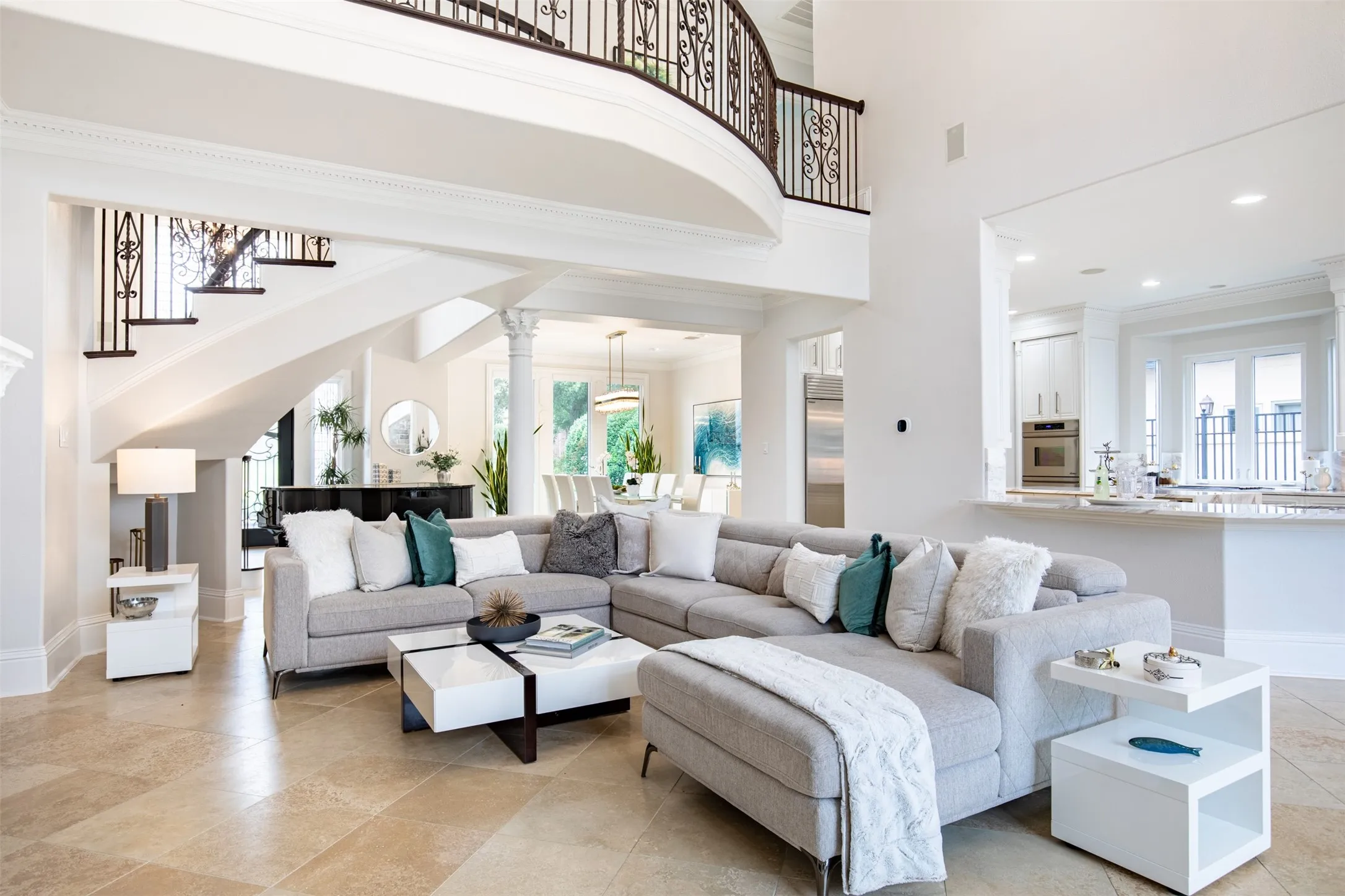 Spacious living area featuring high ceilings, tile flooring, and a grand curved staircase with ornate iron railings
