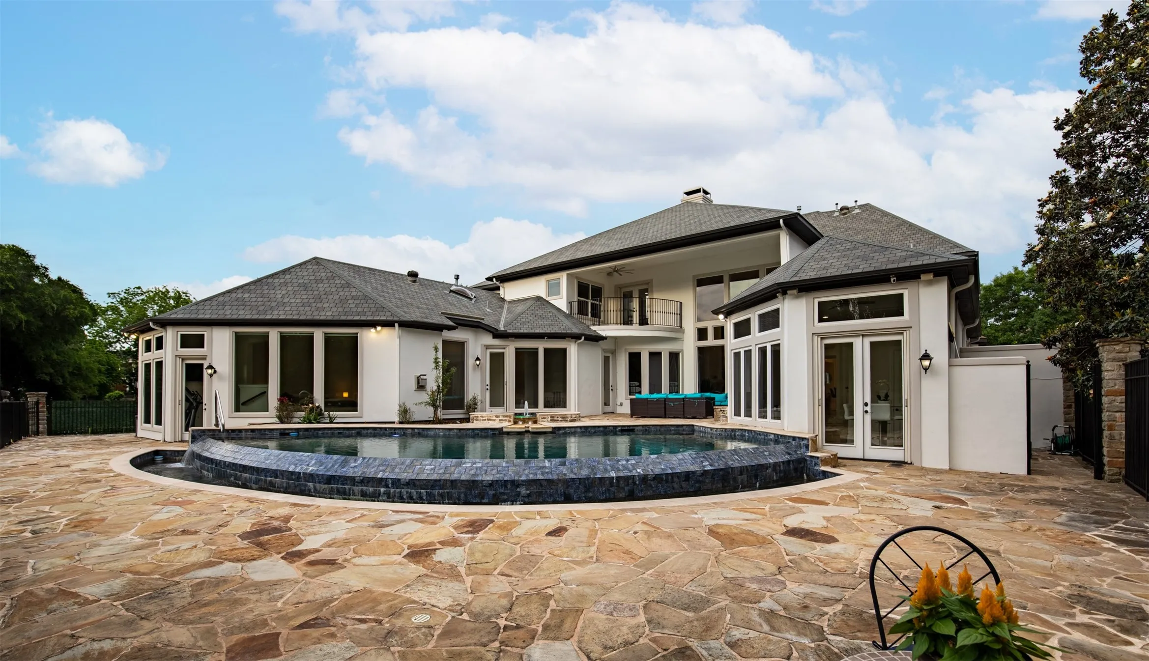 Expansive outdoor living space featuring an irregular flagstone patio surrounding a dark-tiled, curvilinear pool