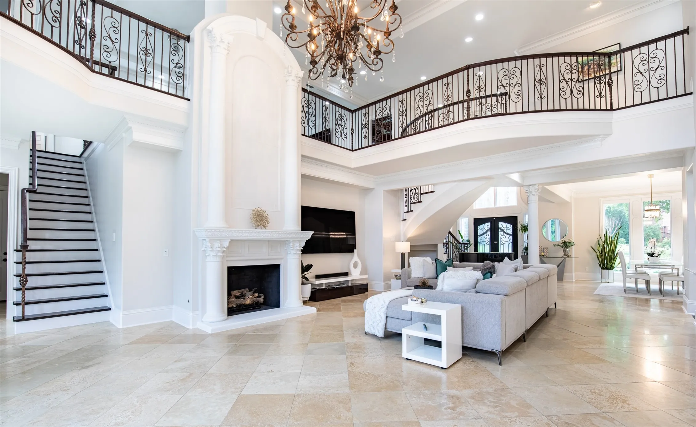 Two-story living area featuring high ceilings, light stone flooring, and a decorative fireplace