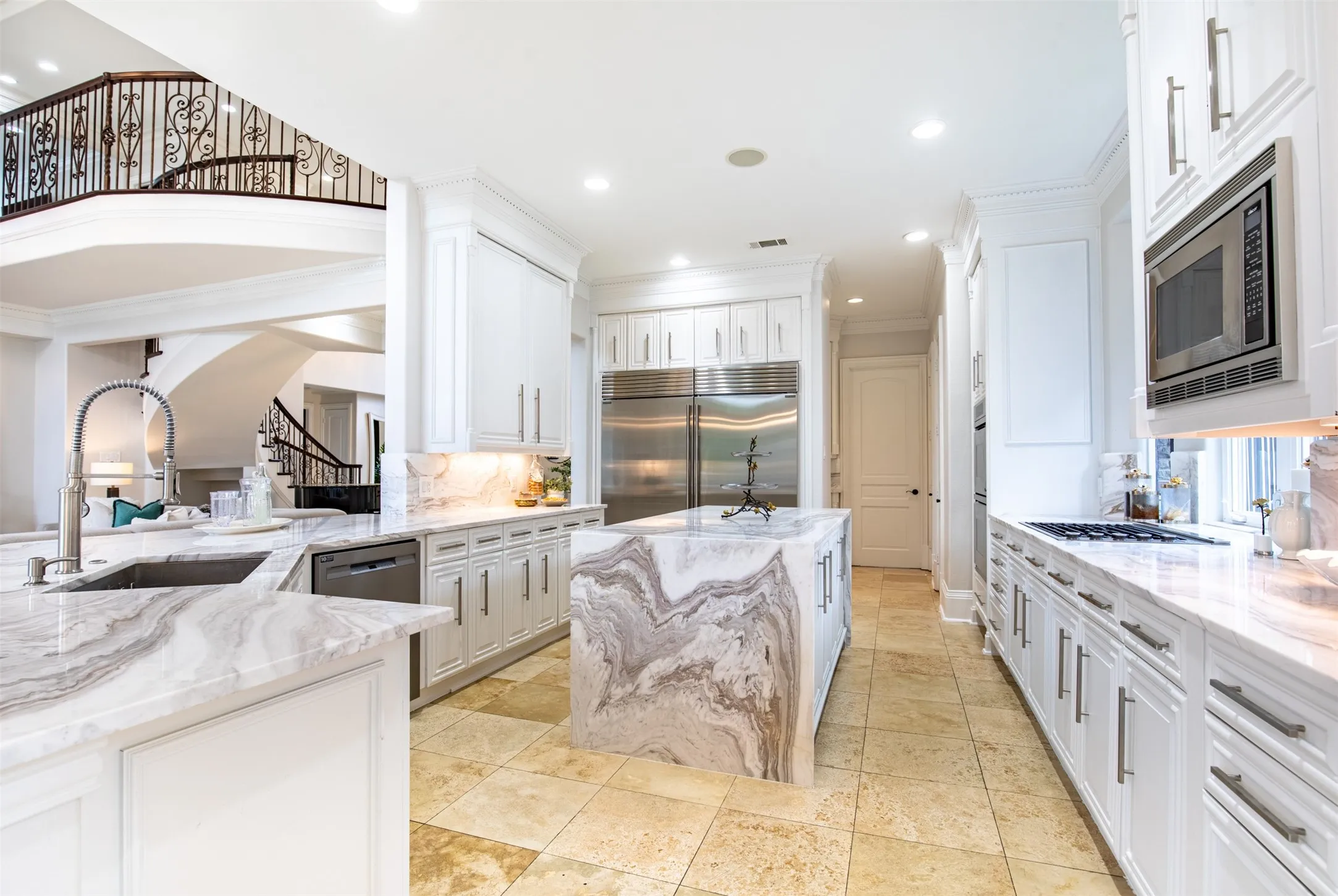 Gourmet kitchen with waterfall-edge island, white cabinetry with brushed nickel hardware, and porcelain countertops with matching backsplashes