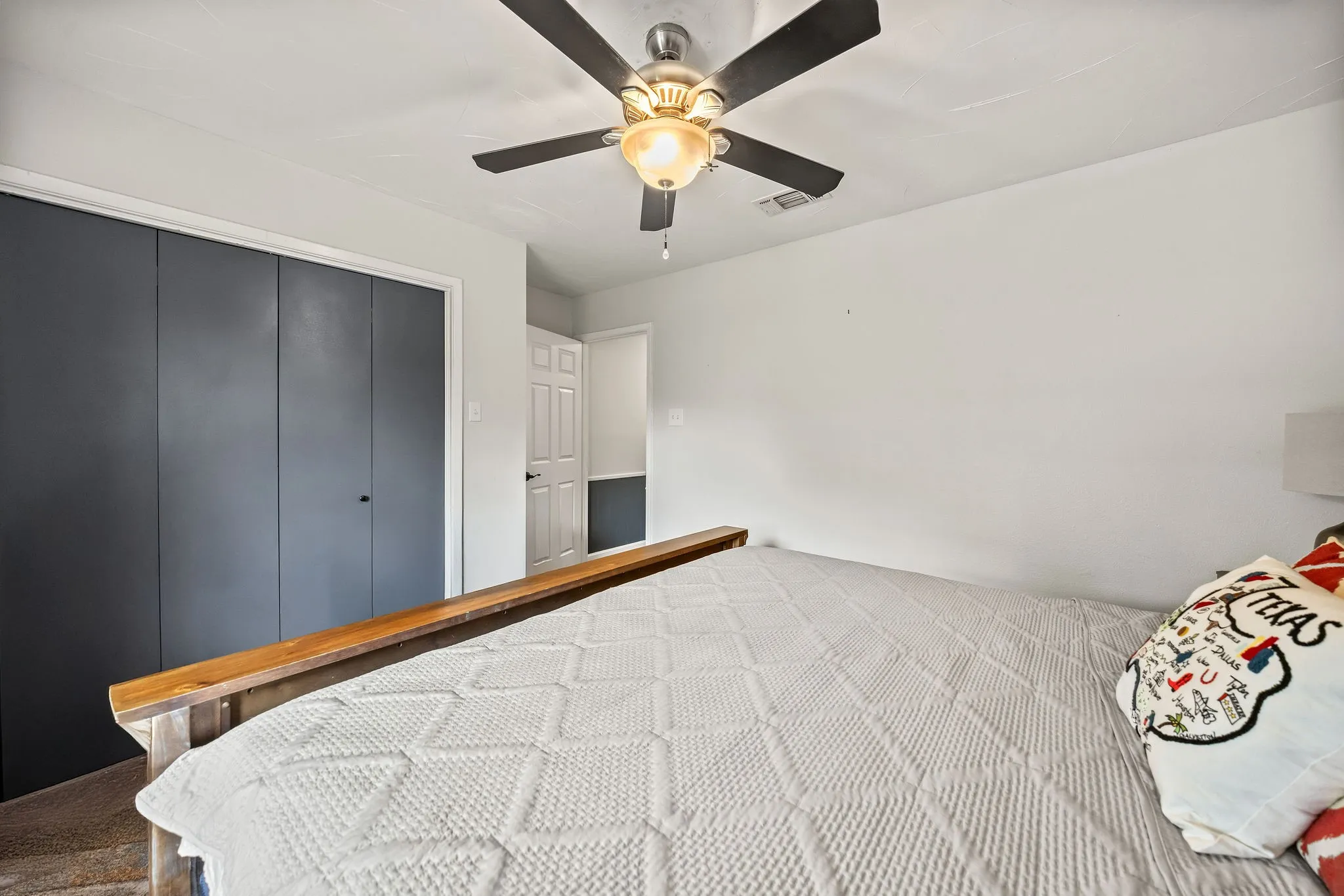 Bedroom featuring a ceiling fan with integrated lighting, white walls, and dark bifold closet doors