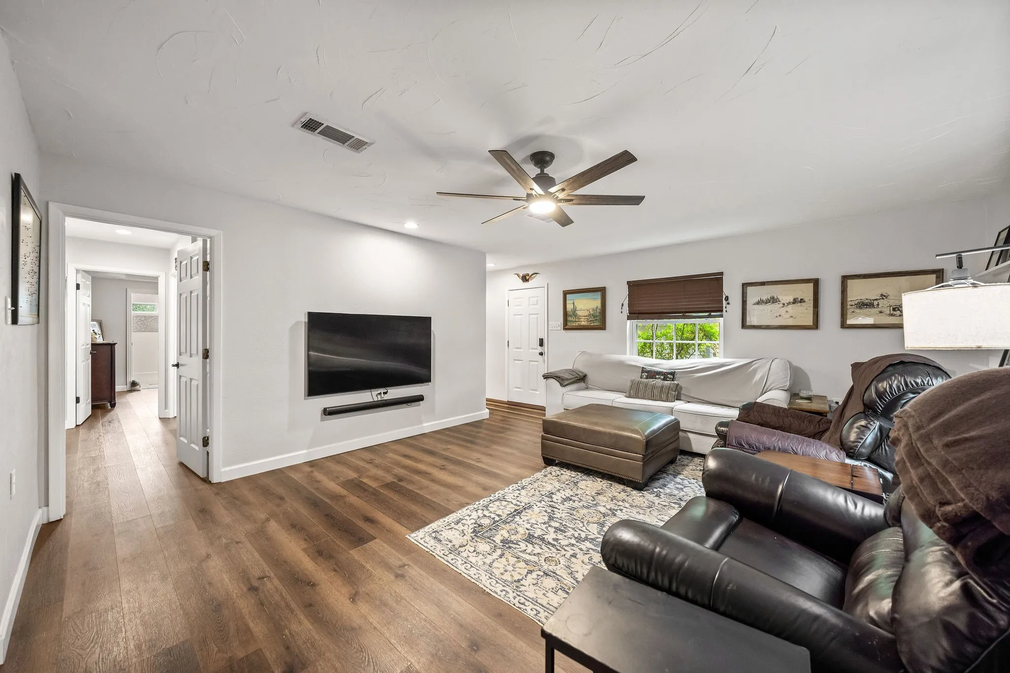 Spacious living area featuring wood-finish flooring, light-toned walls, and recessed lighting