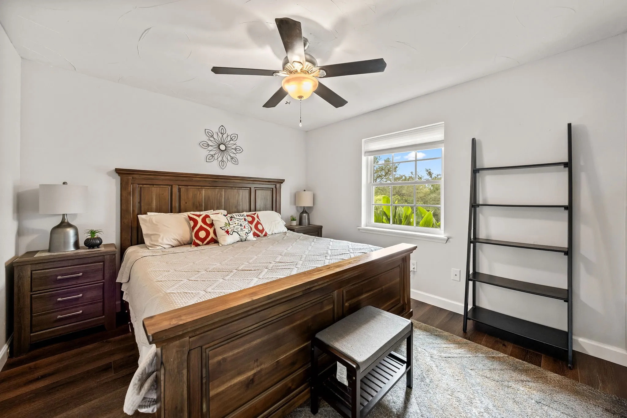 Bedroom featuring wood-finish flooring, a ceiling fan with integrated lighting, and a window with roller shades