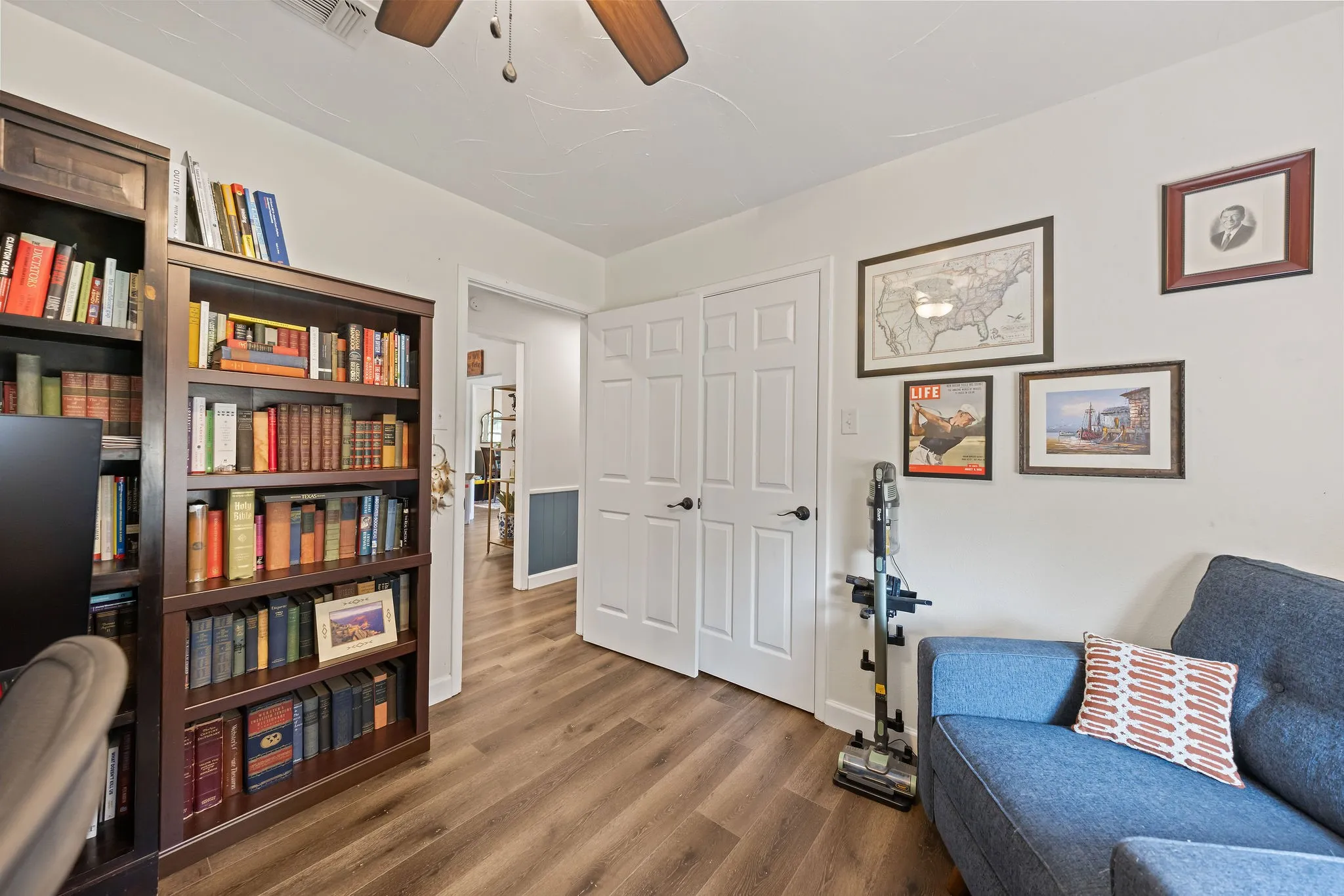 Wood-finish flooring throughout, white walls, and a ceiling fan with light fixture