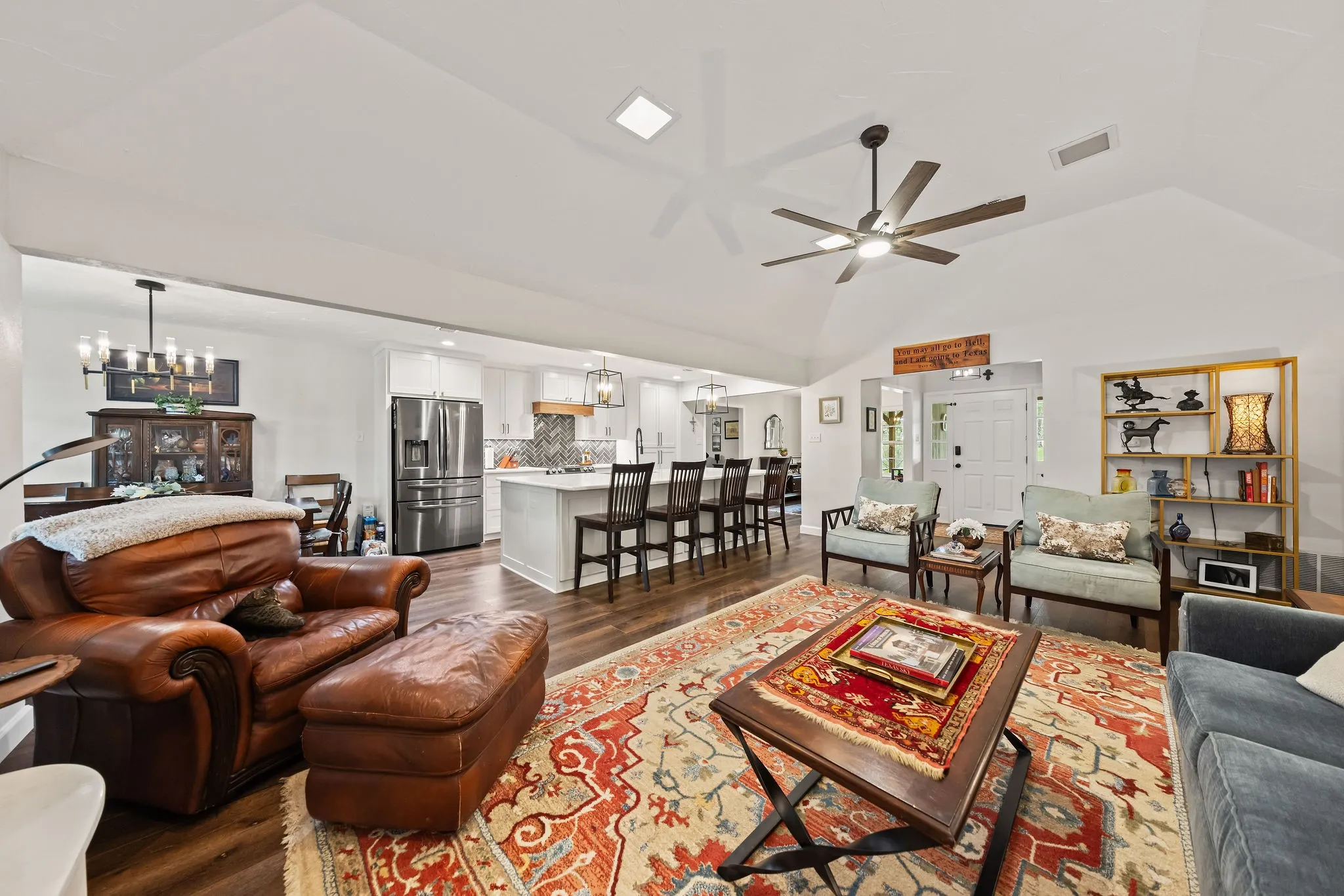 Vaulted ceilings with a ceiling fan highlight this open-concept living area featuring wood-finish flooring