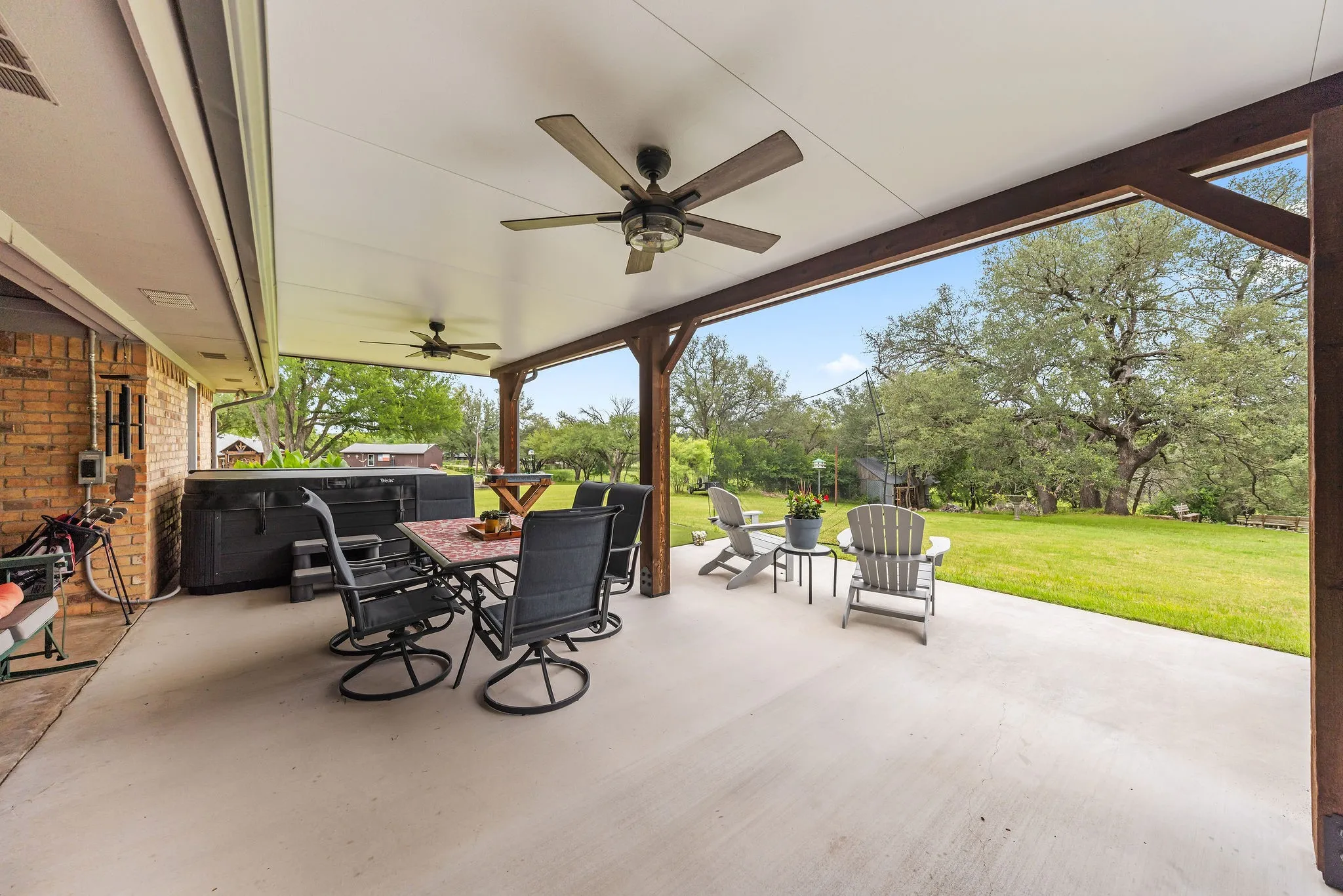 Expansive covered patio featuring a concrete surface, exposed wood beams, and multiple ceiling fans