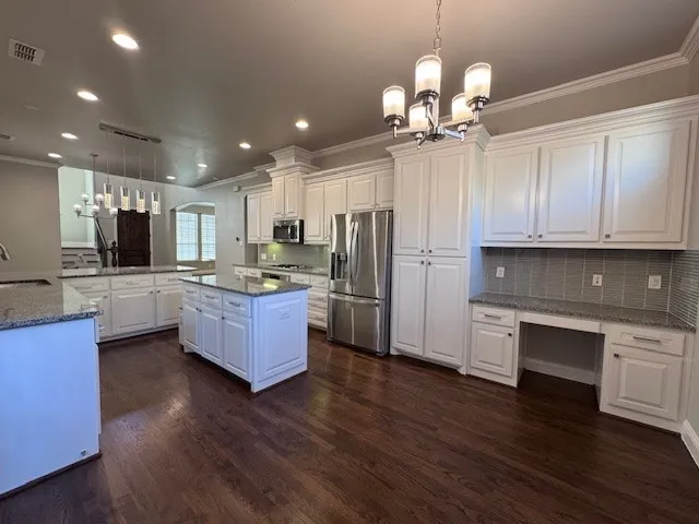 Gourmet kitchen featuring wood-finish flooring, white cabinetry, granite countertops, and stainless steel appliances