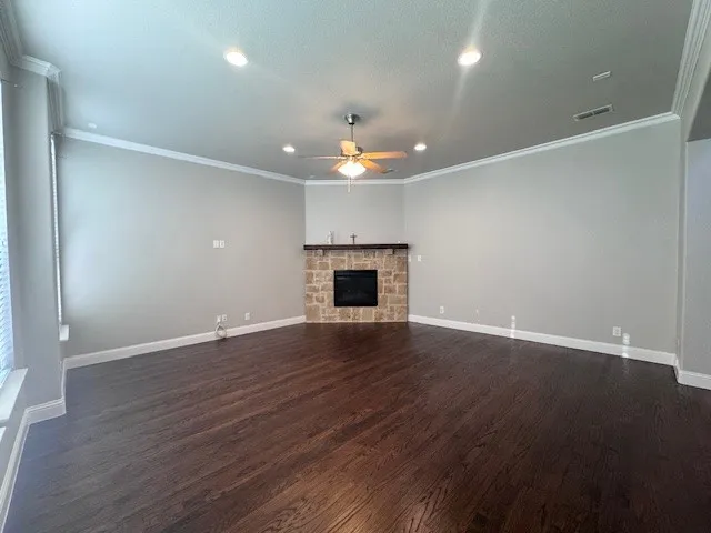 Spacious interior featuring dark wood-finish flooring and a corner fireplace with stone surround and wood mantel