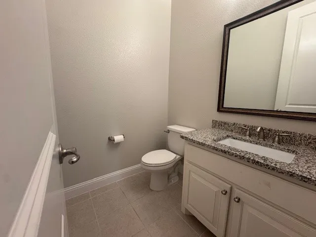 Bathroom featuring a white vanity with a granite-style countertop, undermount sink, and brushed nickel fixtures