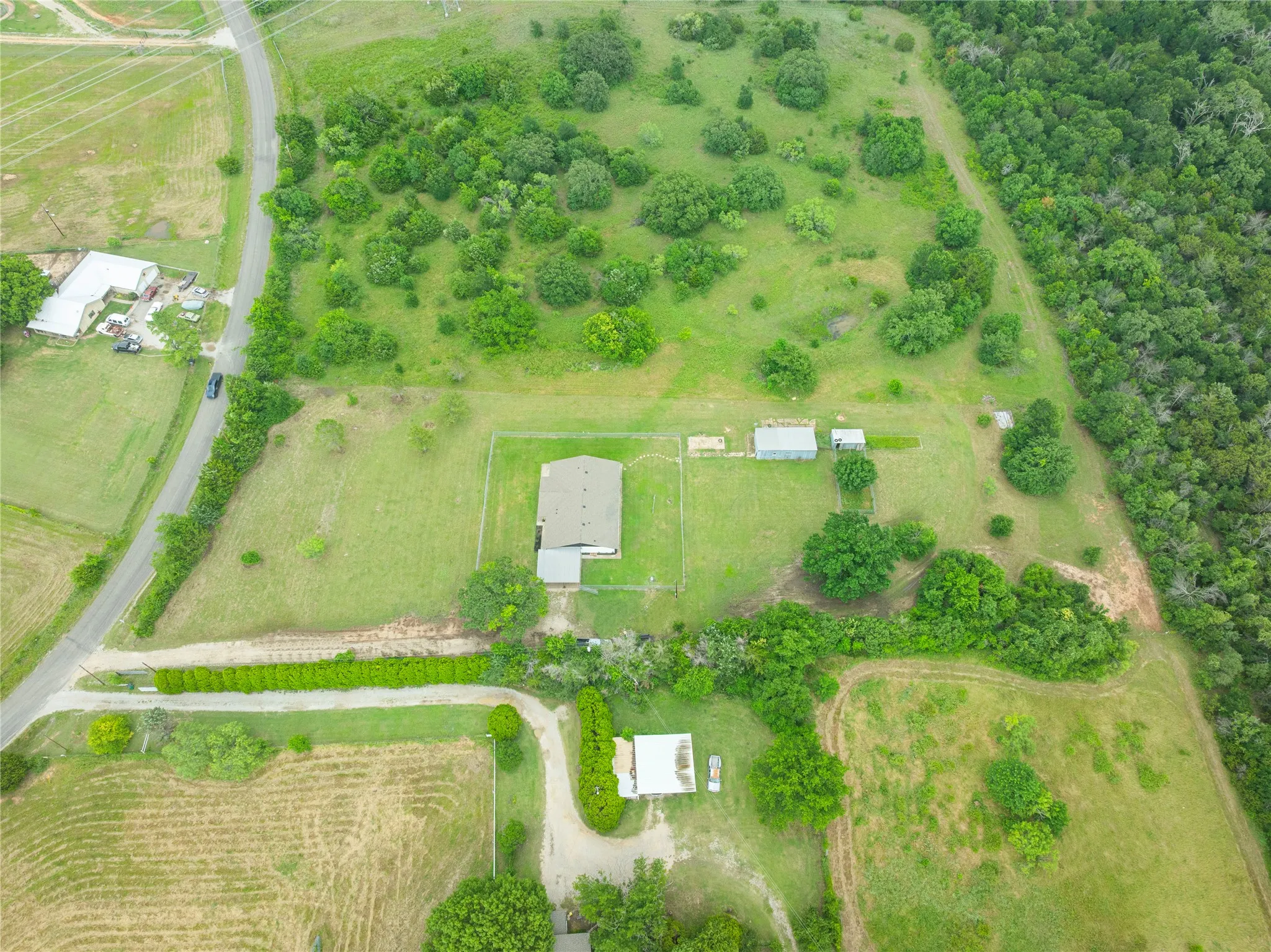 Expansive property featuring a central residence with a gabled roof, multiple outbuildings, and a perimeter fence