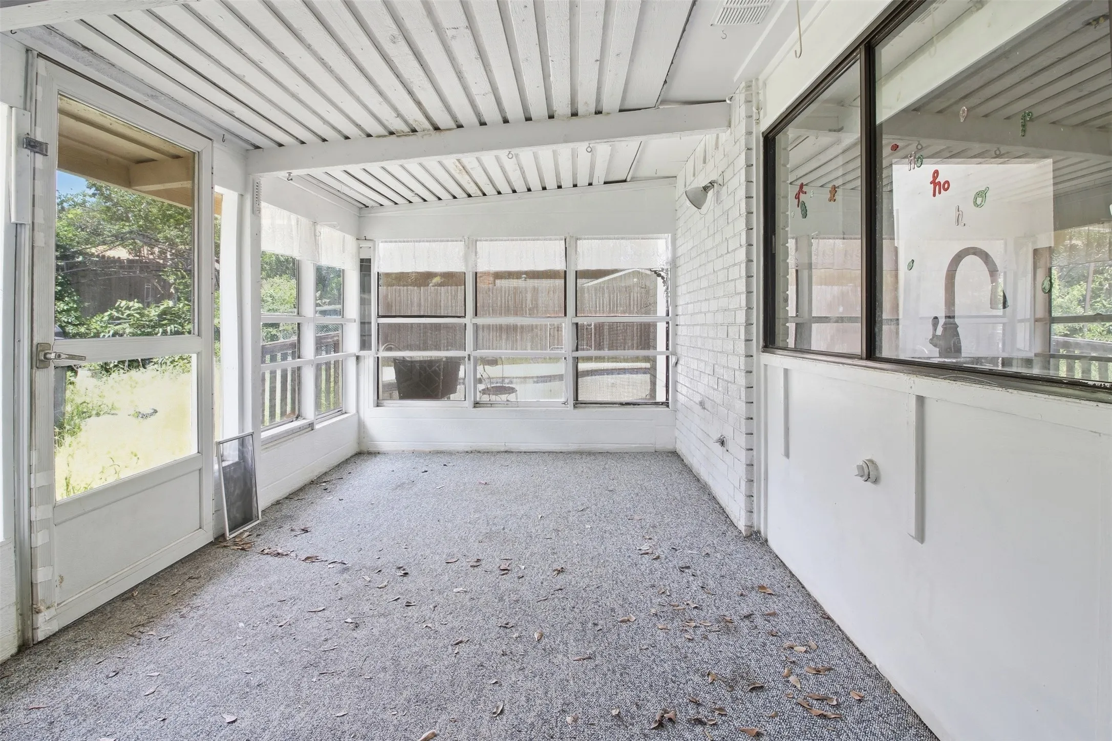 Screened-in porch featuring a full-light screen door, multiple windows, a white wood-slat ceiling, and a grey textured floor
