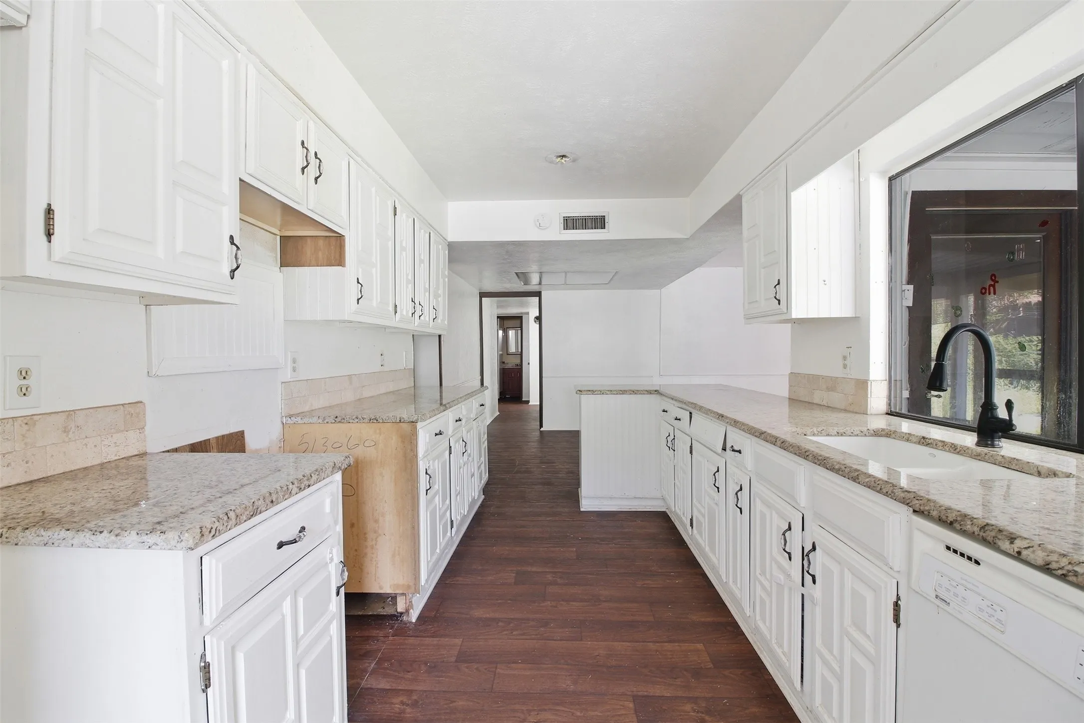 Kitchen featuring extensive white cabinetry, granite-finish countertops, wood-finish flooring, a stainless steel sink, and a black gooseneck faucet
