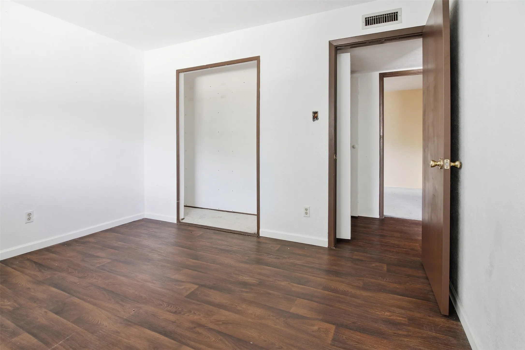 Room featuring wood-finish flooring, white walls, and a recessed closet space