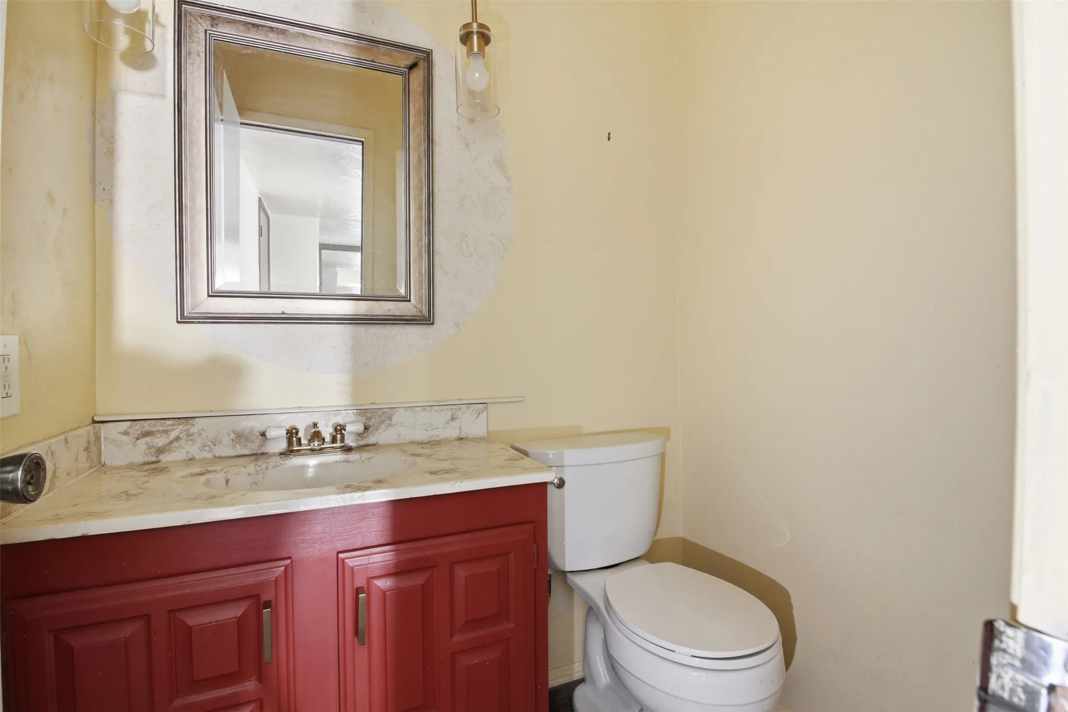 Powder room featuring a red-painted vanity with a light-toned countertop, an undermount sink, and a framed wall mirror