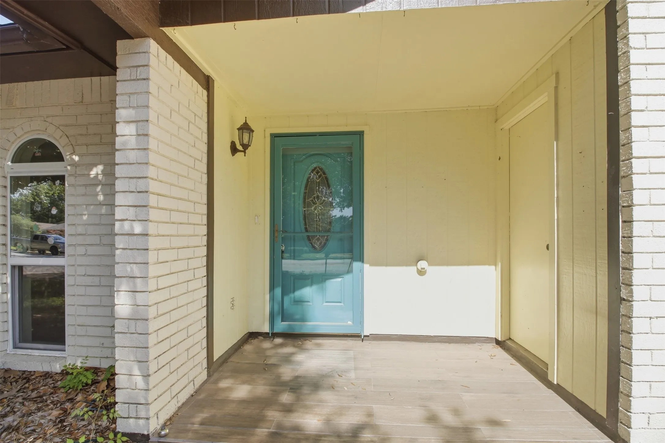 Covered front porch featuring a teal entry door with an oval glass insert and a screen door