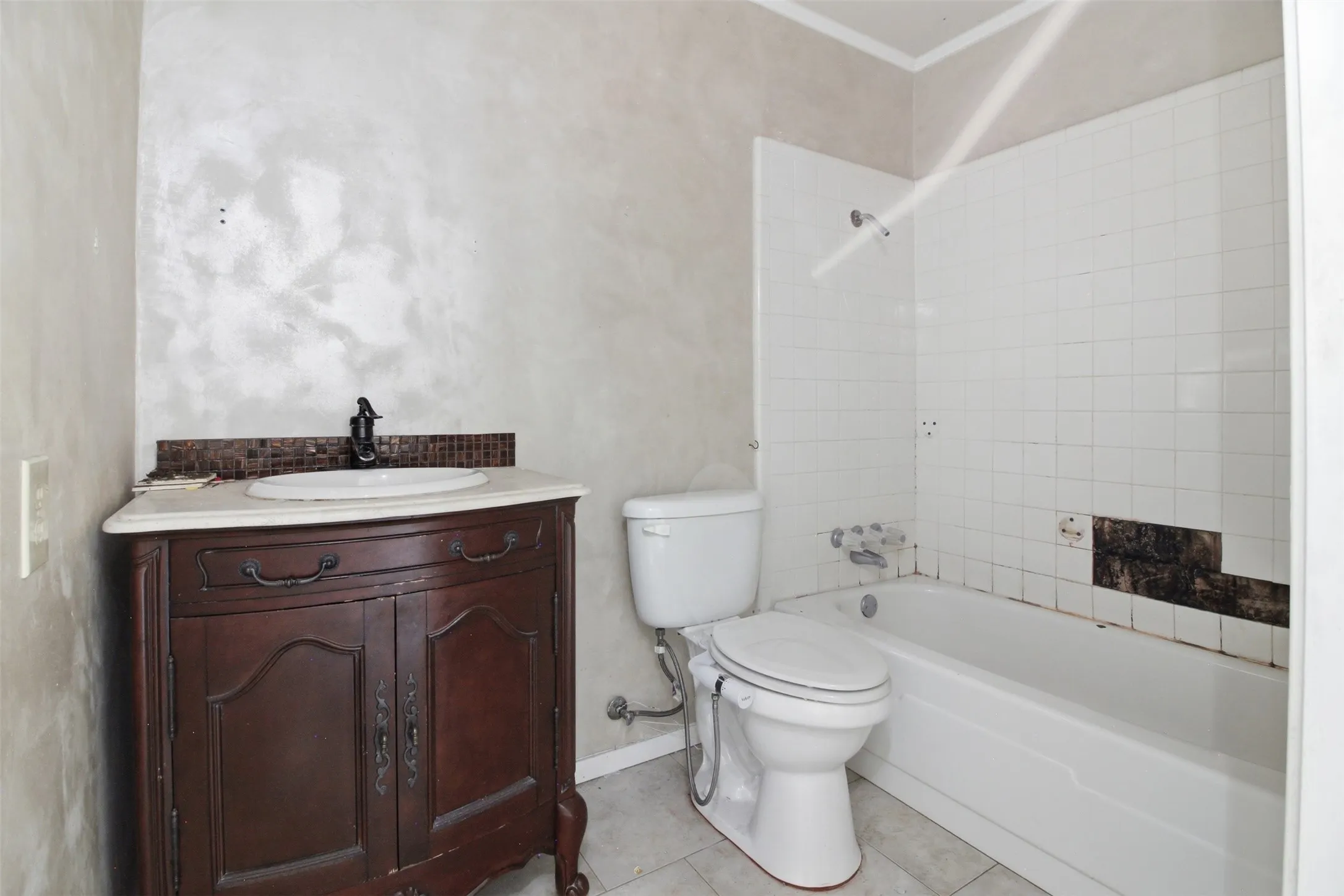 Bathroom featuring a vanity with a white countertop and oval basin, dark wood-finish cabinetry, and a tile backsplash