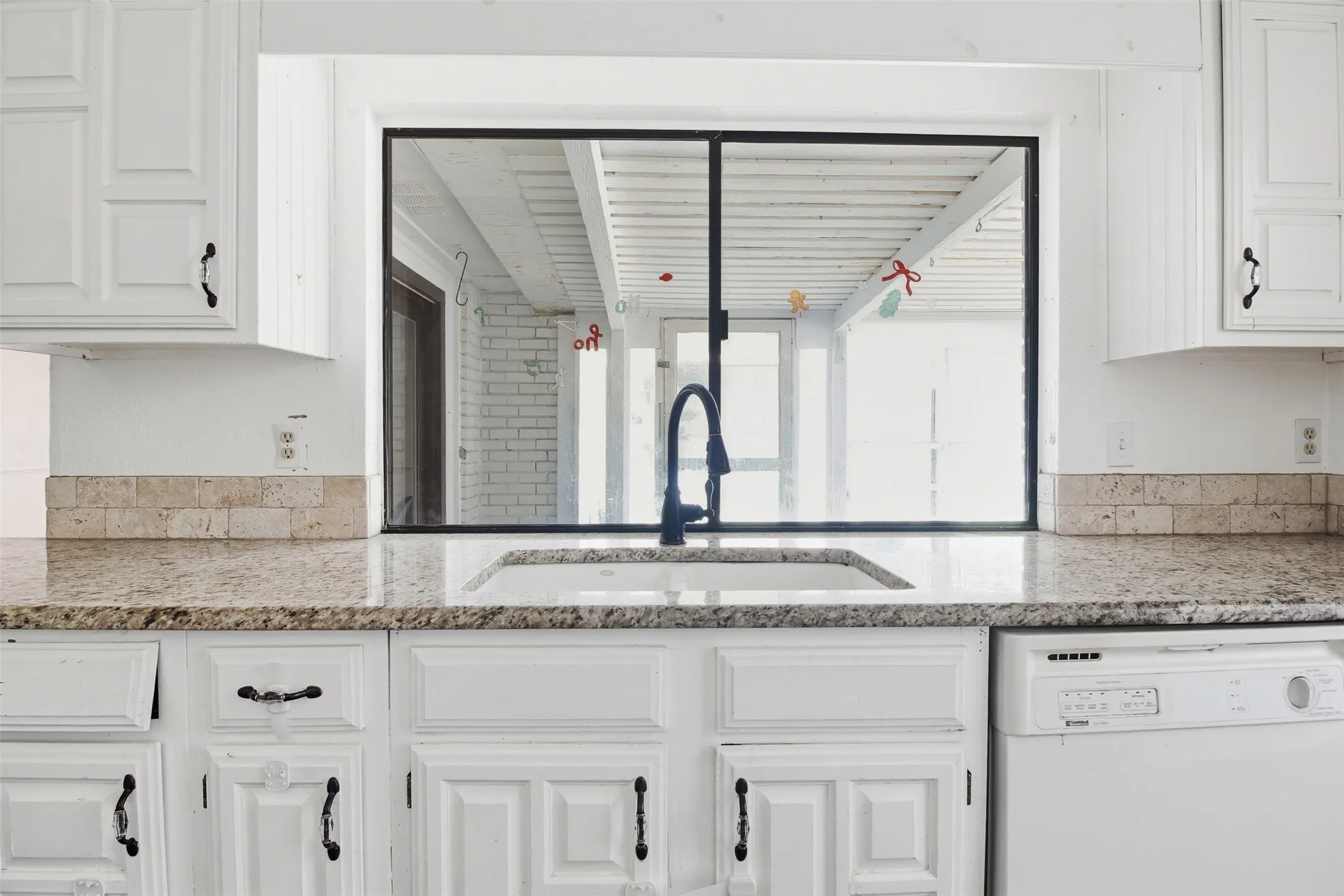 Kitchen featuring white cabinetry, granite countertops, an undermount sink, and a black faucet