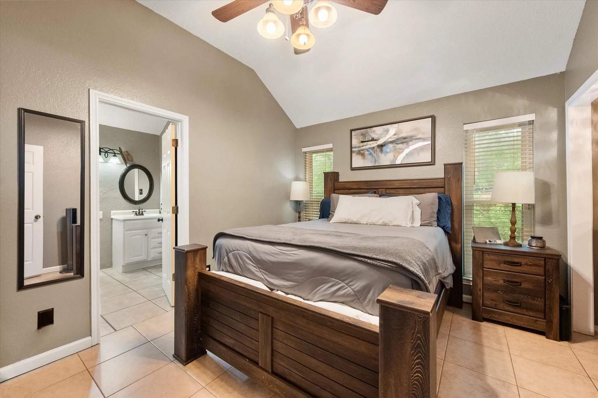 Vaulted ceiling with tile flooring and a ceiling fan