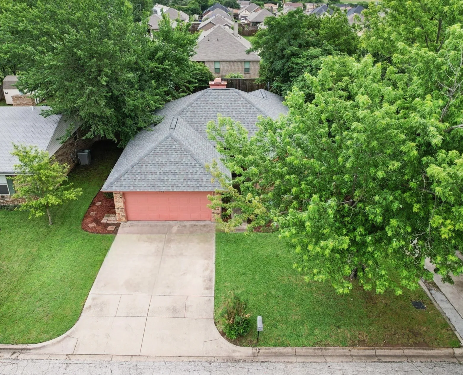 Single-story residence featuring a gray shingle roof and a red garage door