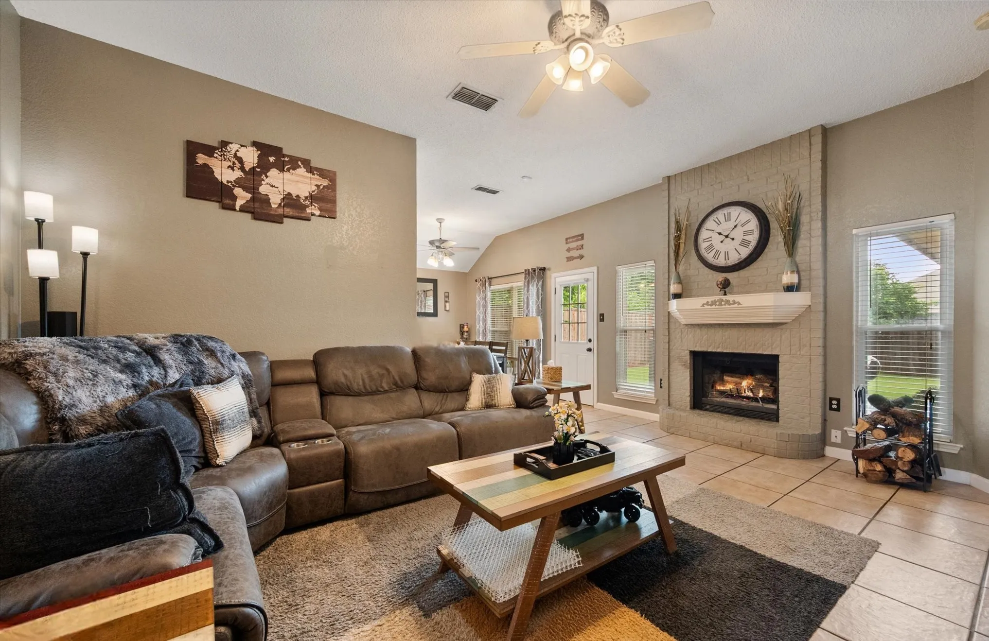 Living area featuring a brick fireplace with a mantle, tile flooring, and multiple windows