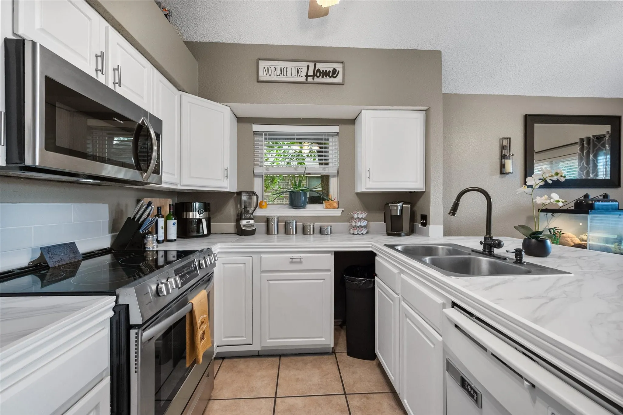 U-shaped kitchen featuring white cabinetry, light-toned countertops, and stainless steel appliances
