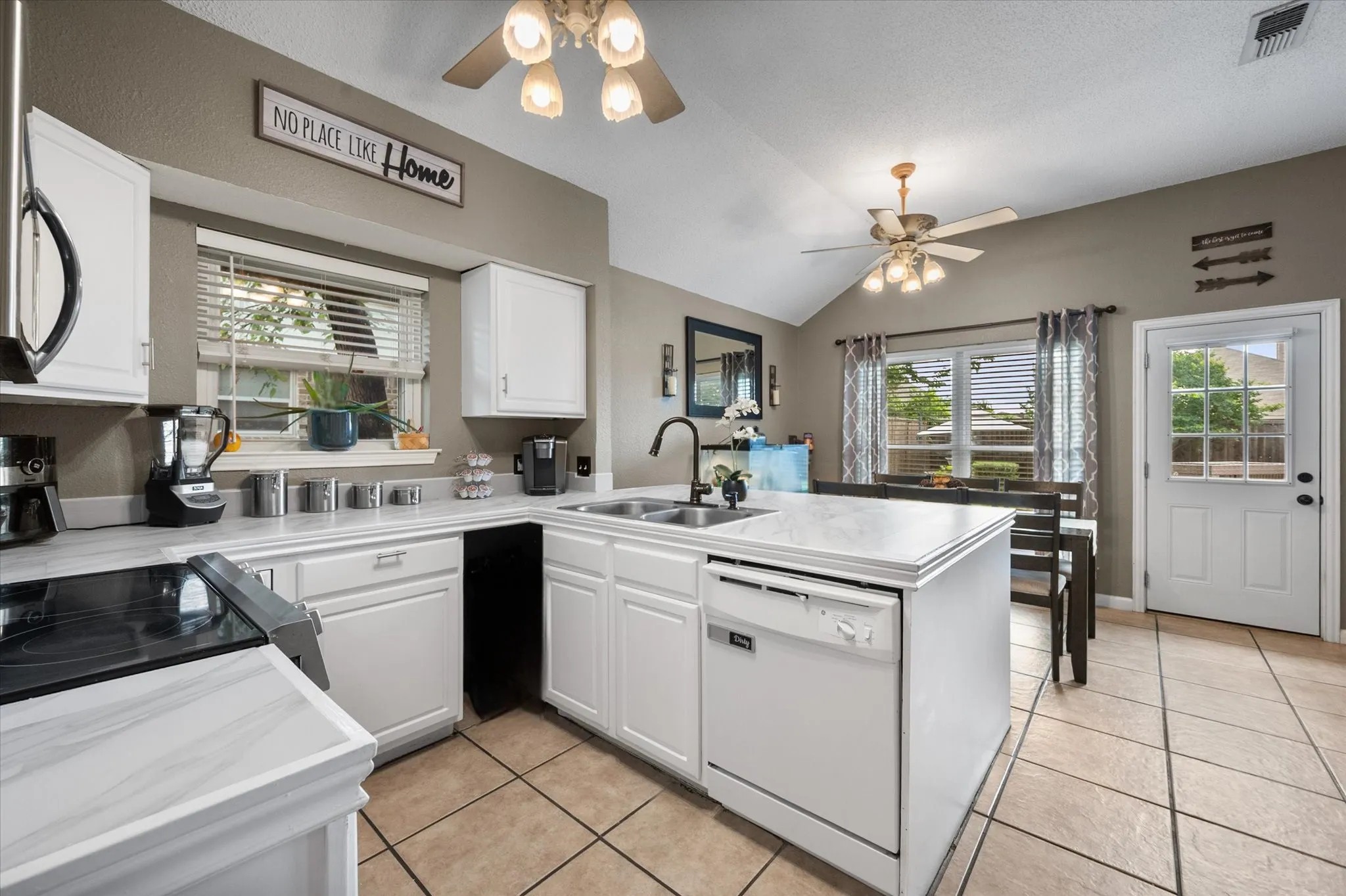 Kitchen featuring white cabinetry, light-toned countertops, and a built-in dishwasher