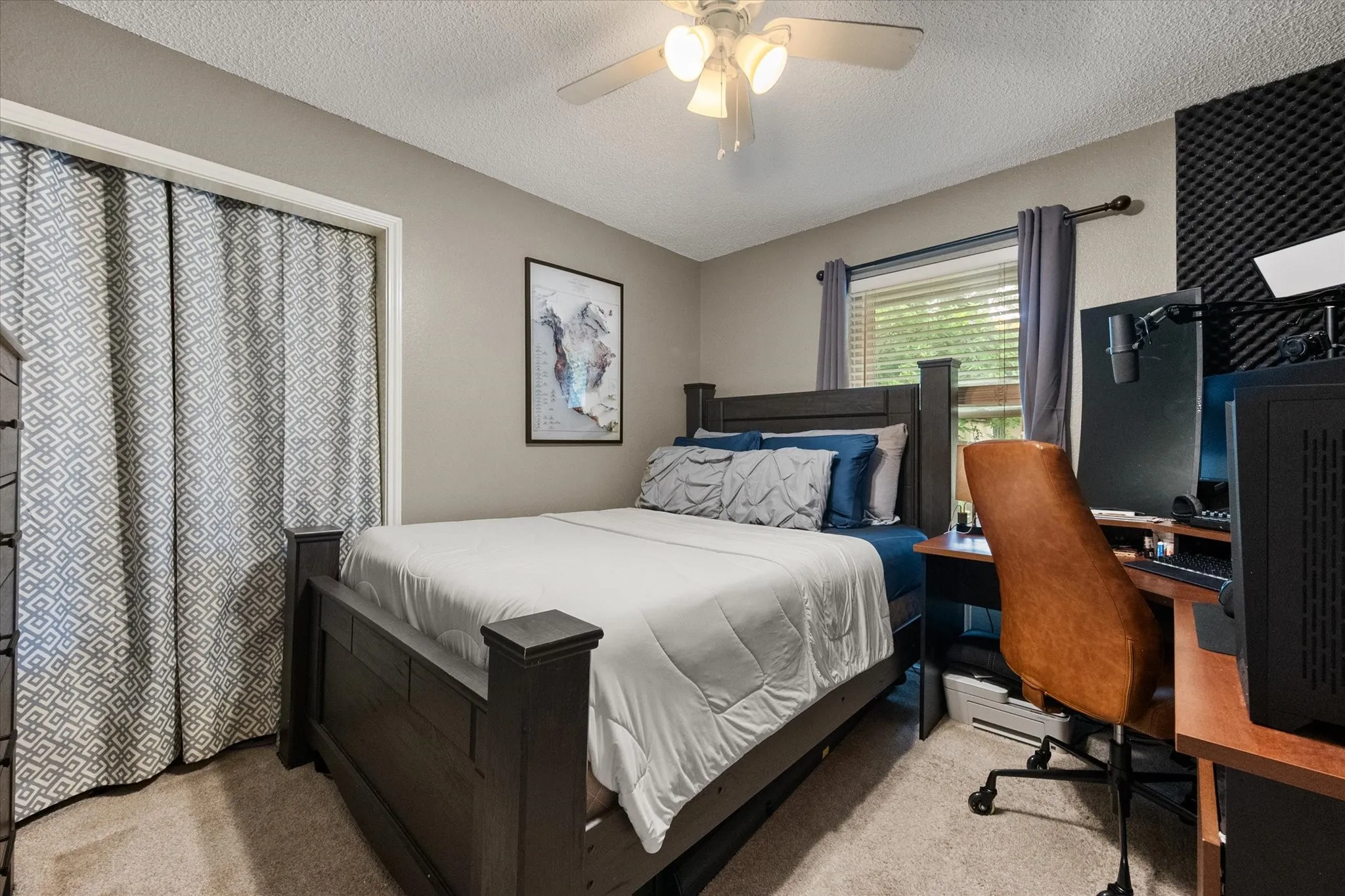 Carpeted room featuring a window with blinds and dark curtains, neutral wall paint, and a ceiling fan with light fixture