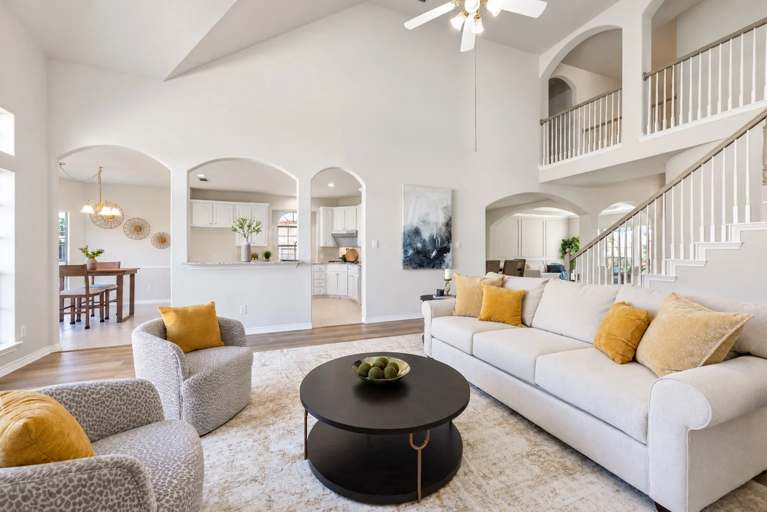 Vaulted ceilings, a full staircase with white balusters, and arched doorways define this living space