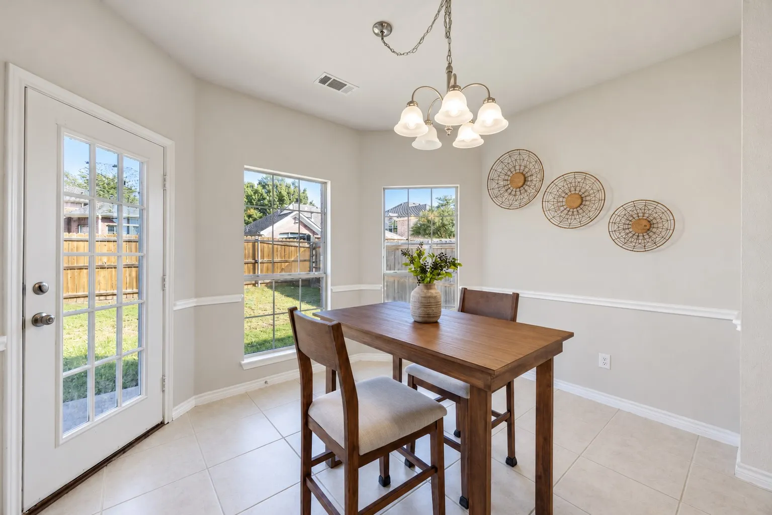 Recessed lighting, warm neutral wall tones, chair rail molding, tiled flooring, and a glass-paneled door