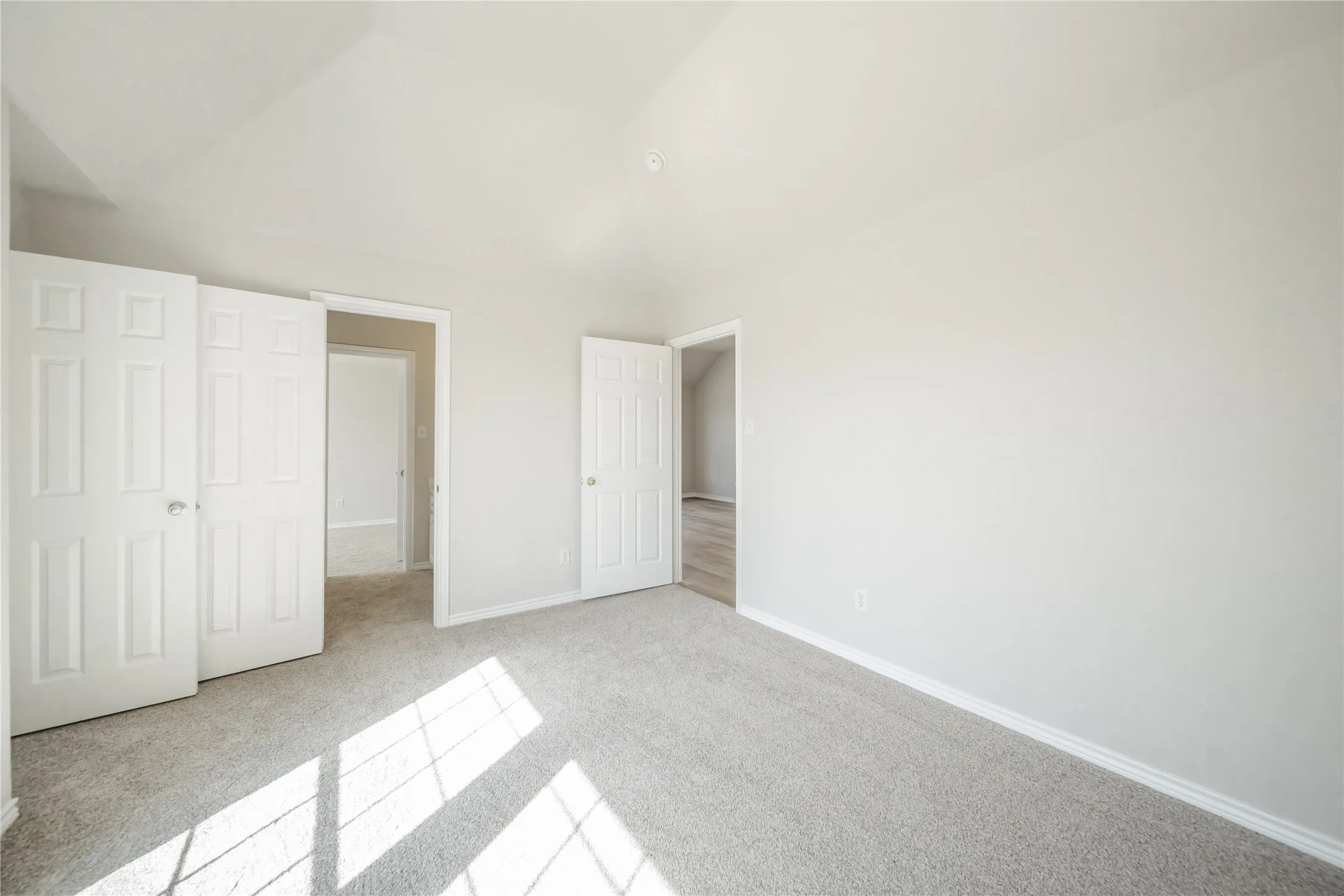 Carpeted room featuring light gray walls, white baseboards, and white six-panel doors