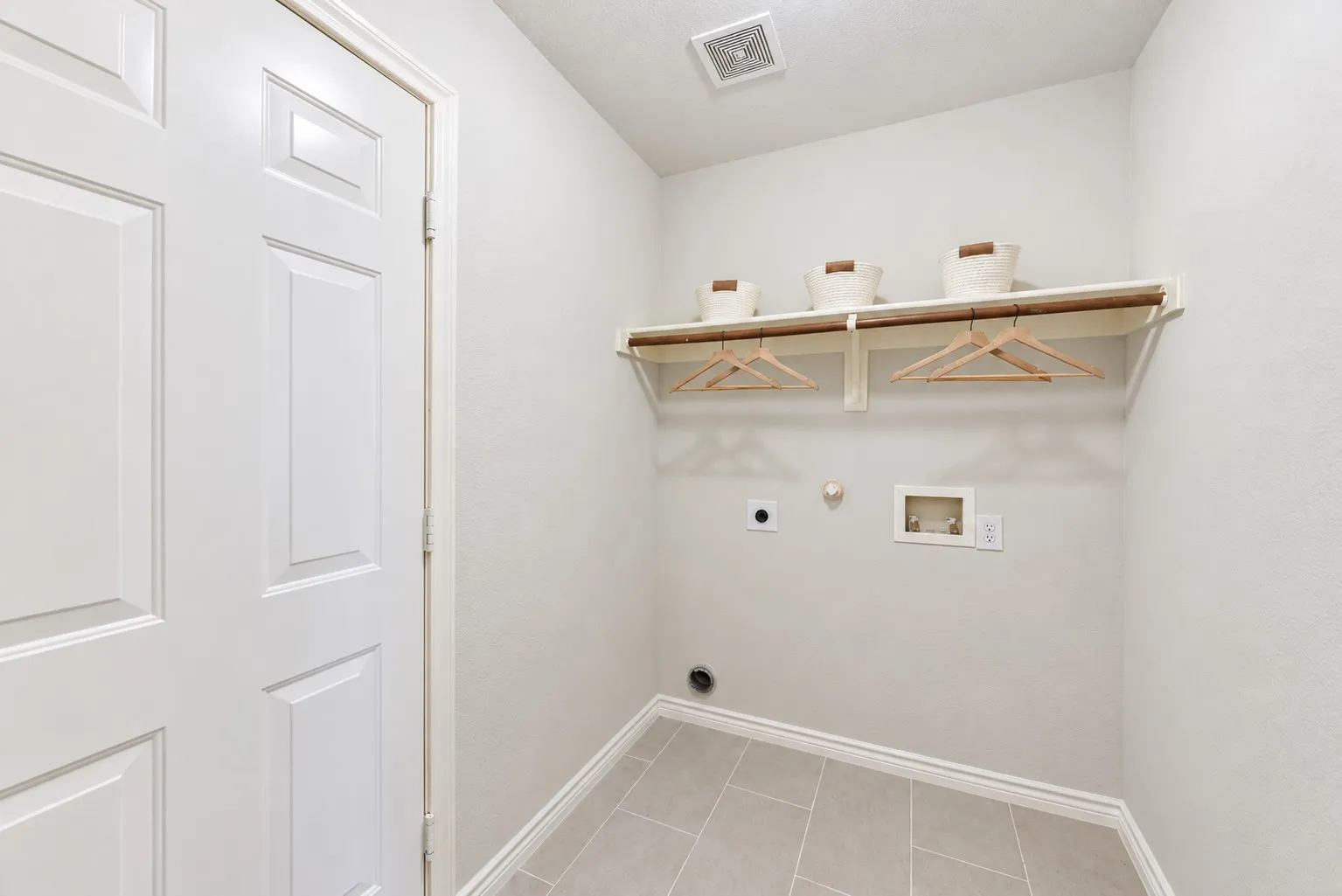 Tile flooring, white paneled door, built-in shelving, and a hanging rod