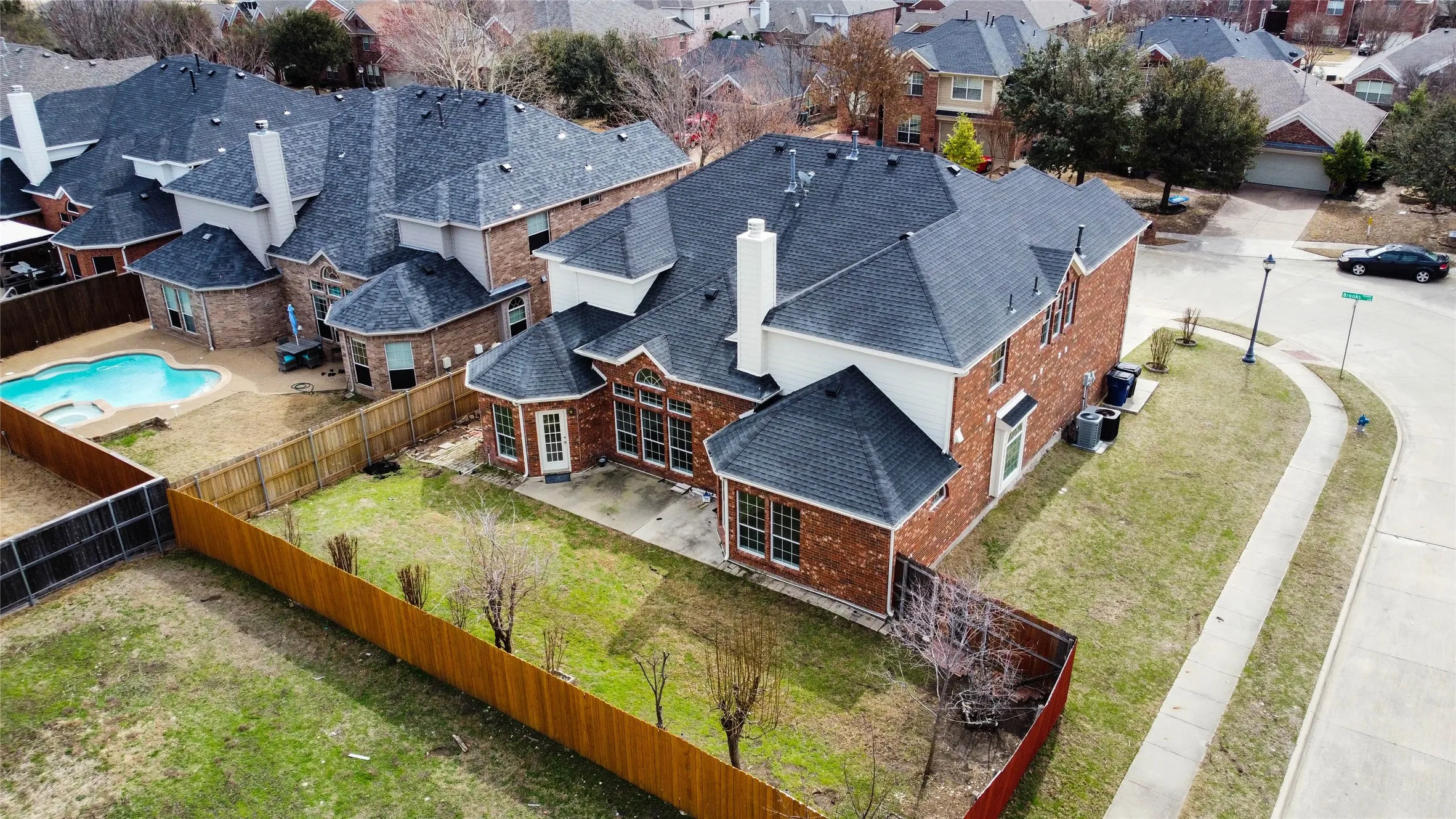 Brick exterior residence with a private fenced backyard, paved patio, and mature landscaping