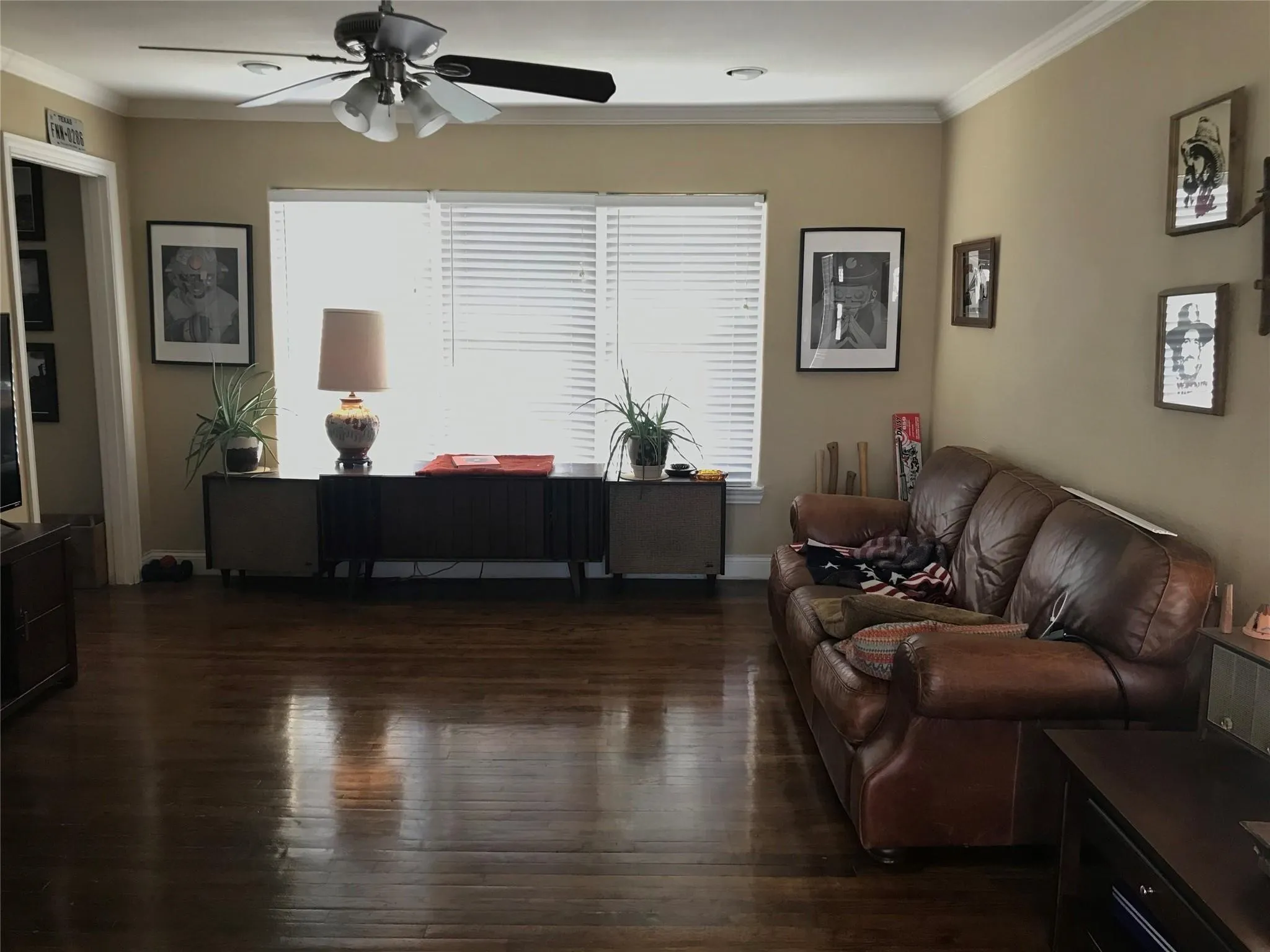 Spacious room featuring rich wood flooring, crown molding, and a ceiling fan with integrated lighting
