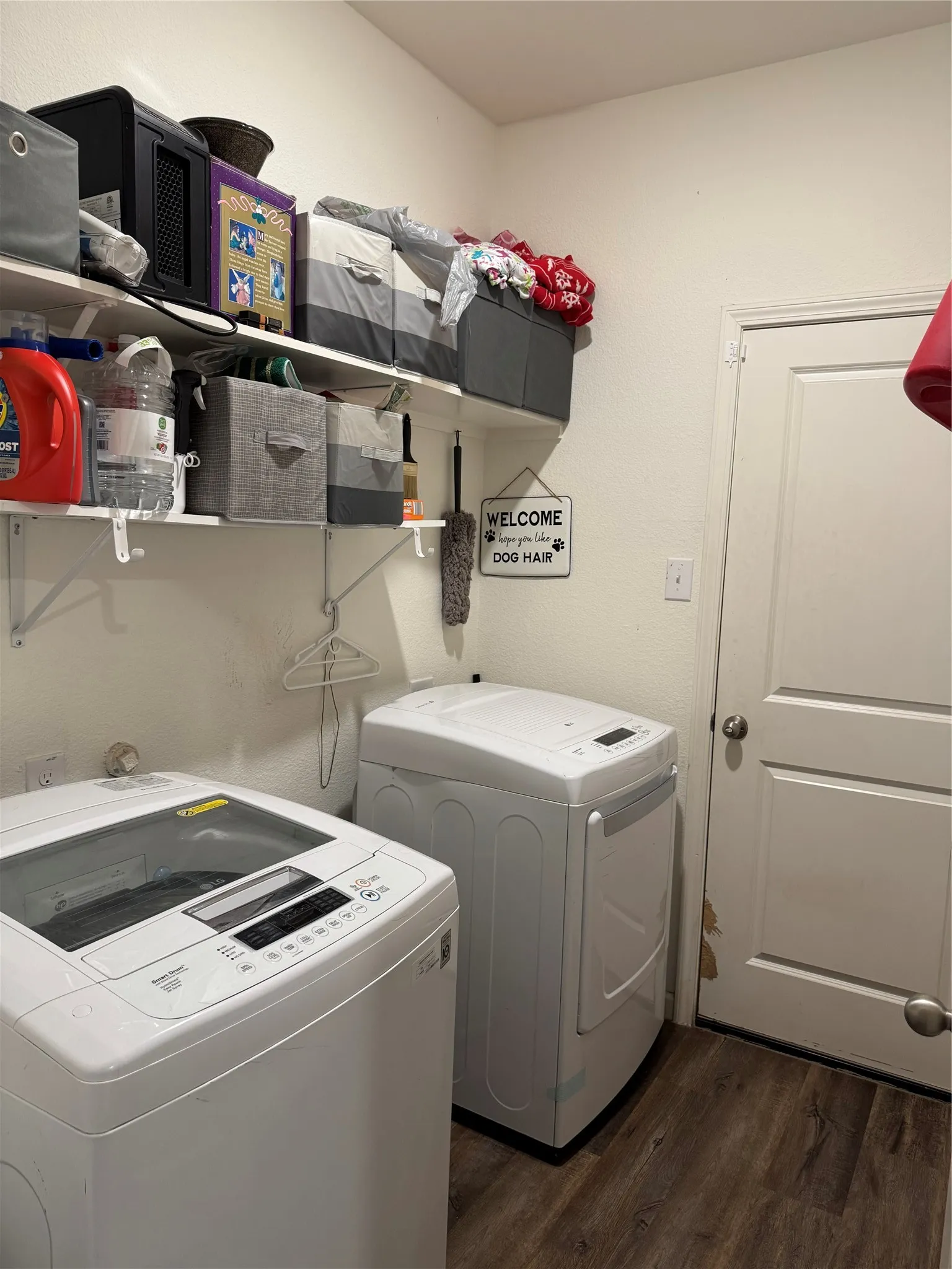 Laundry area featuring wood-finish flooring, white walls, and built-in shelving